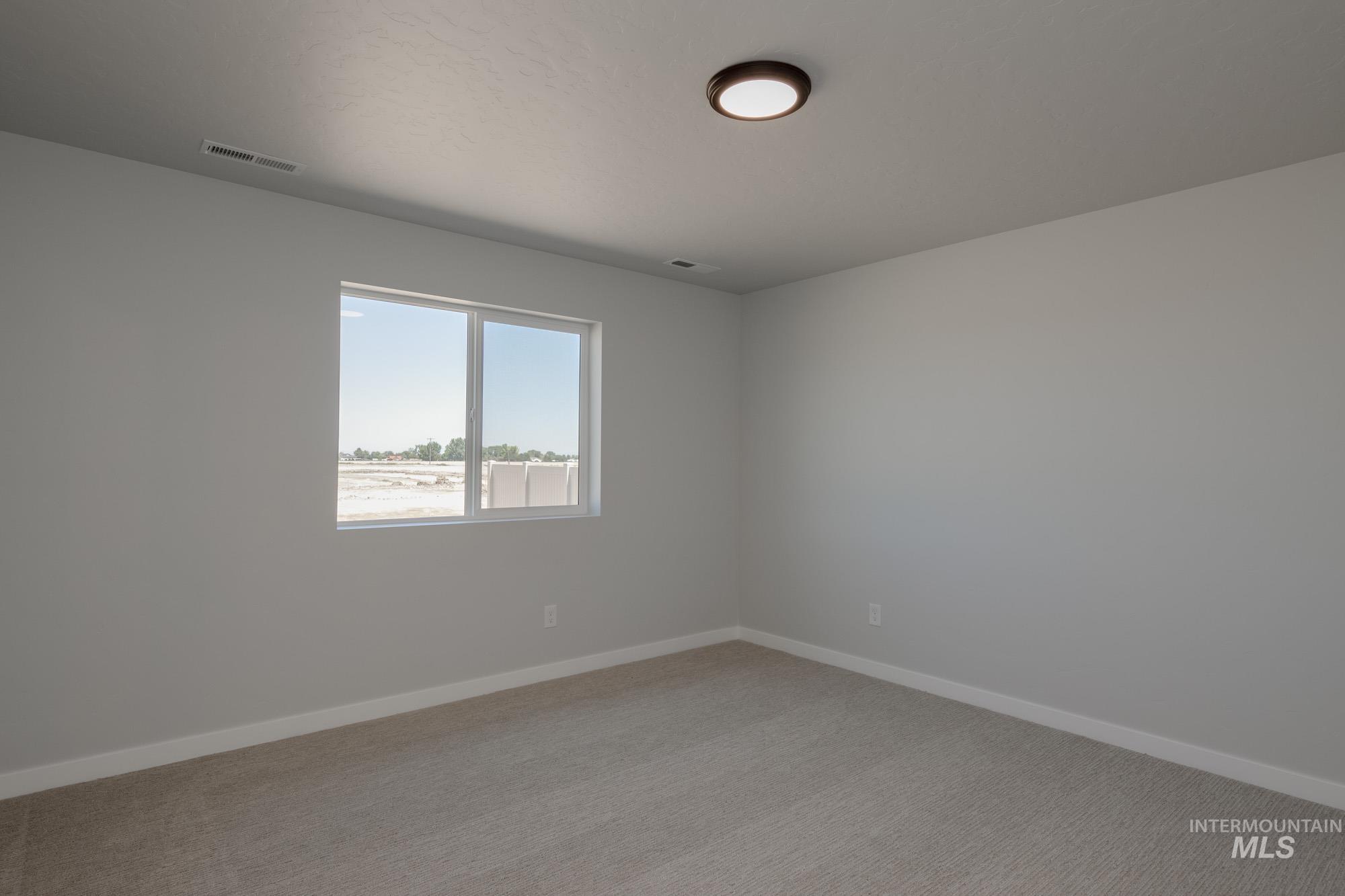 Spare room featuring light carpet and baseboards