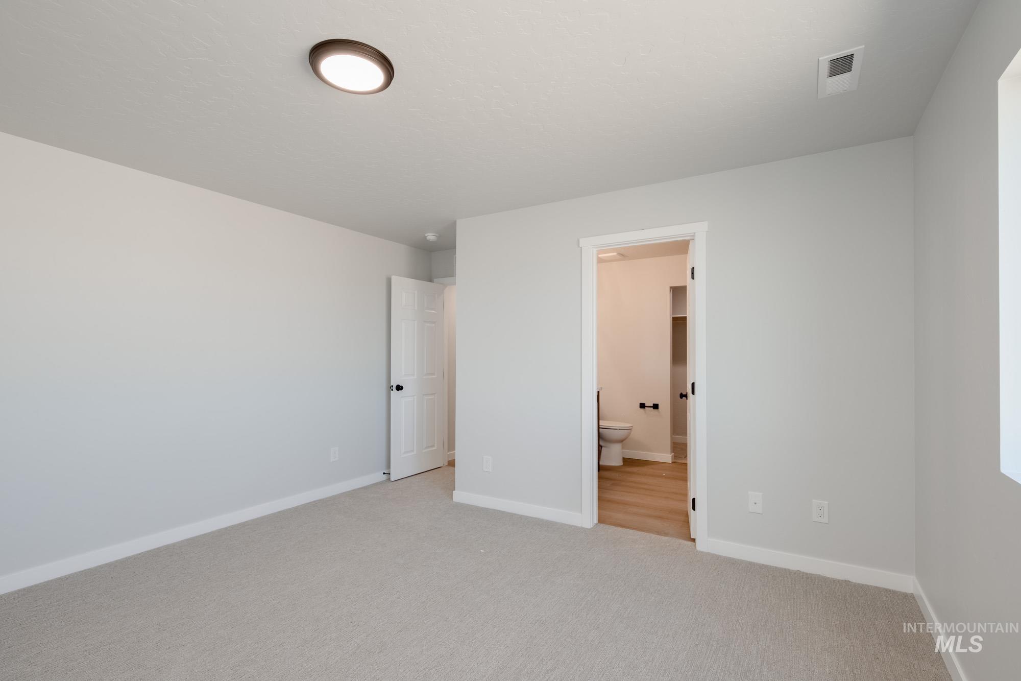 Unfurnished bedroom with carpet flooring and ensuite bath
