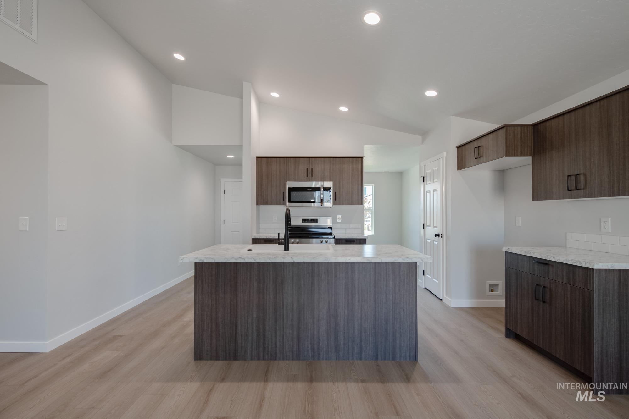Kitchen with a kitchen island with sink, modern cabinets, light wood-style floors, recessed lighting, and stainless steel appliances