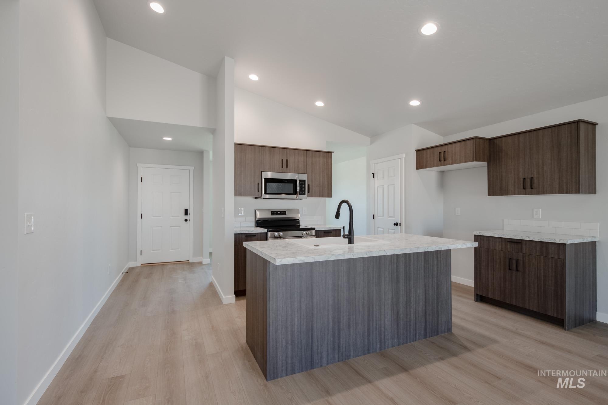 Kitchen featuring recessed lighting, stainless steel appliances, light wood-type flooring, a center island with sink, and modern cabinets