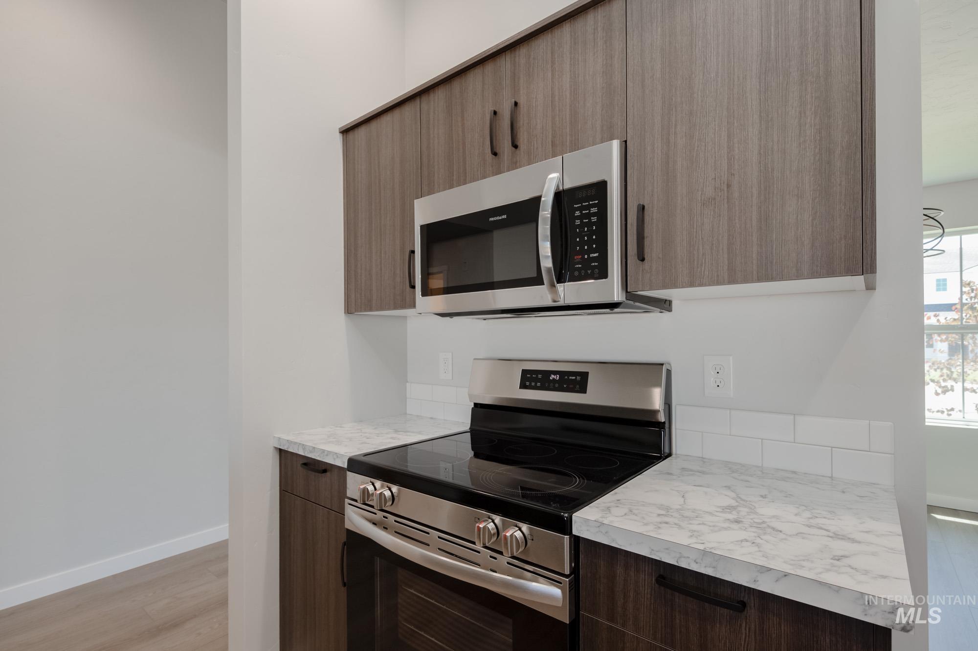 Kitchen with stainless steel appliances, light countertops, modern cabinets, and light wood-type flooring