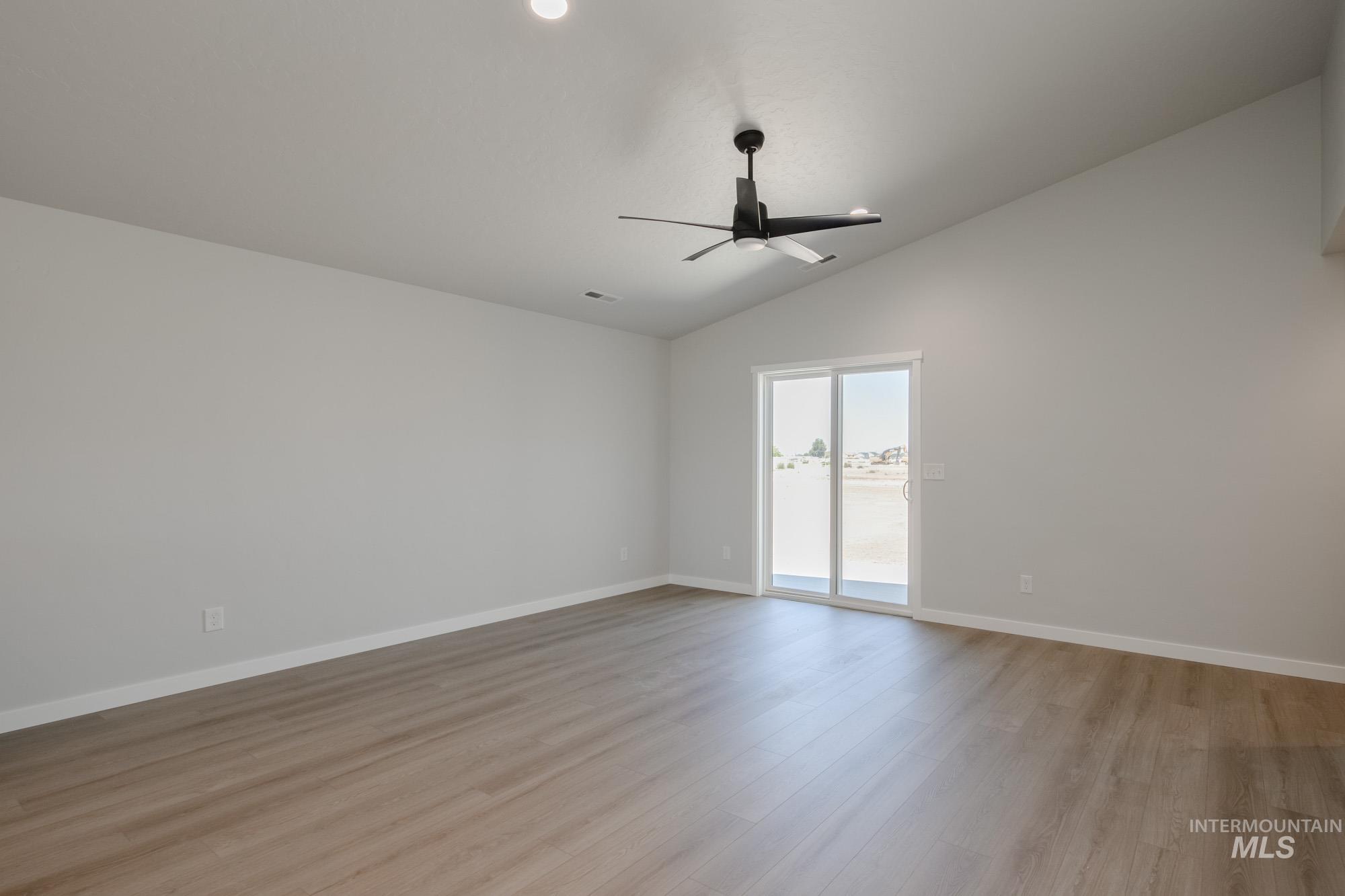 Empty room with light wood finished floors, lofted ceiling, and ceiling fan