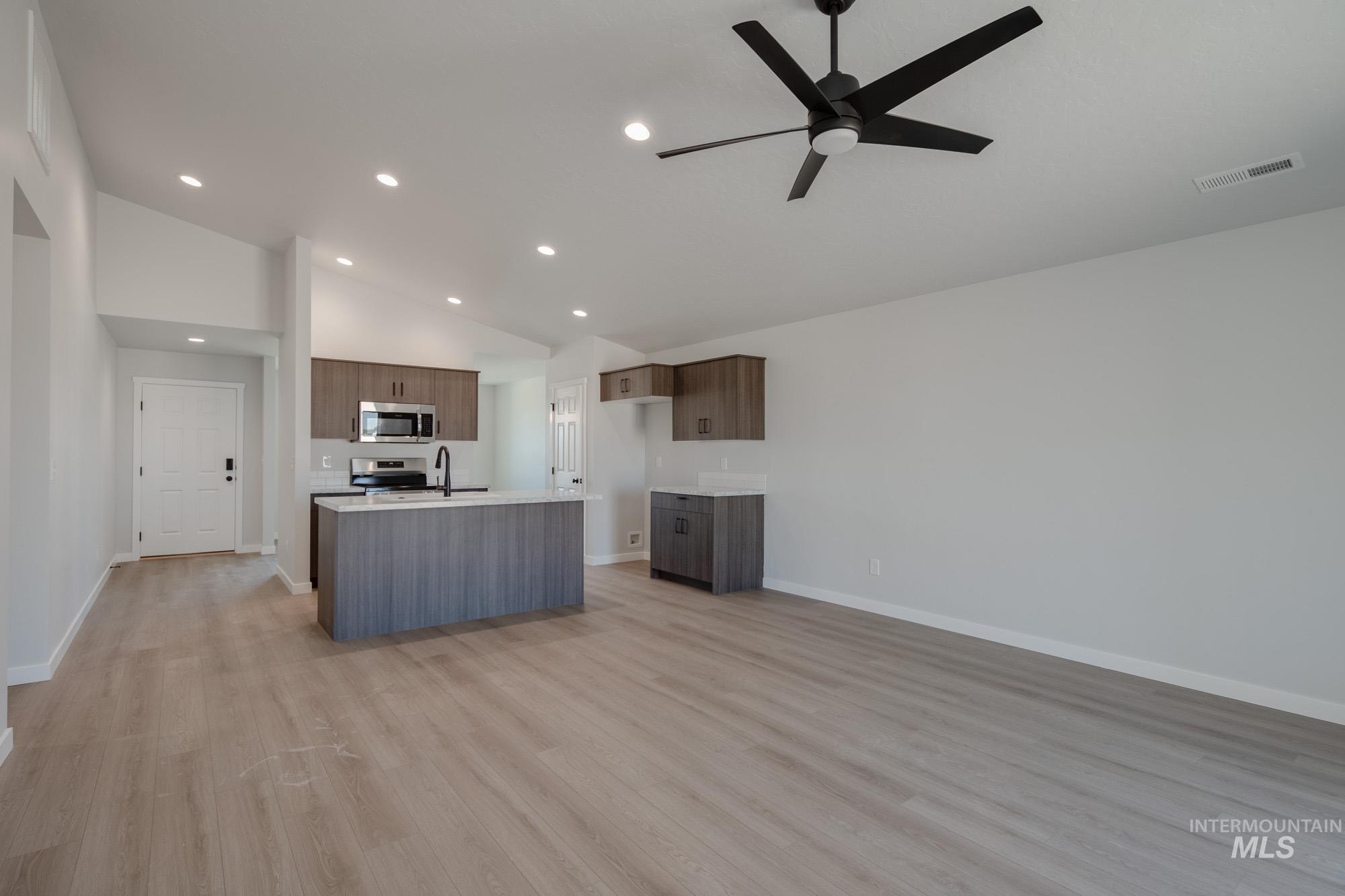 Kitchen featuring open floor plan, light wood-style floors, a center island with sink, recessed lighting, and appliances with stainless steel finishes