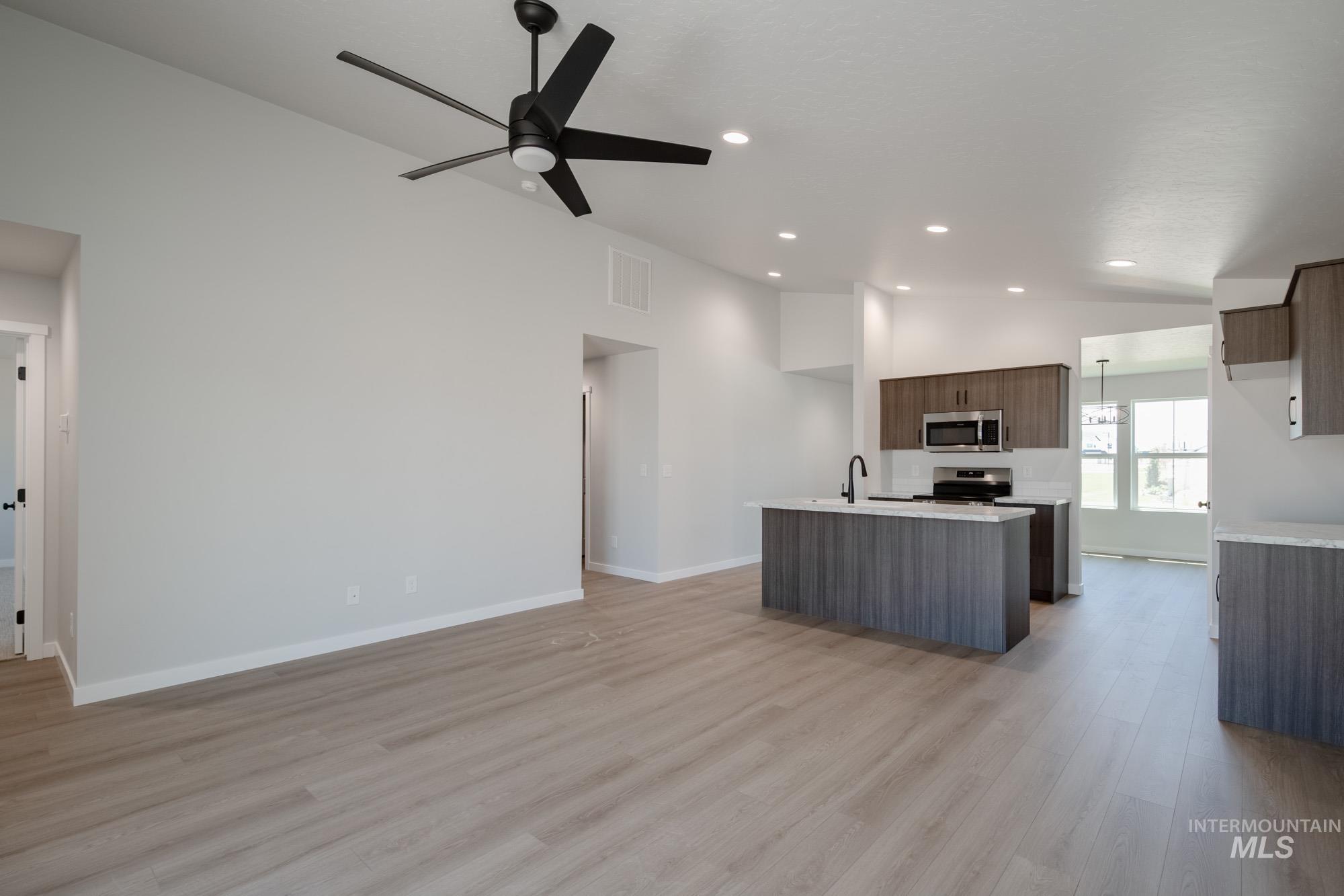 Kitchen with a center island with sink, light wood finished floors, stainless steel appliances, open floor plan, and recessed lighting