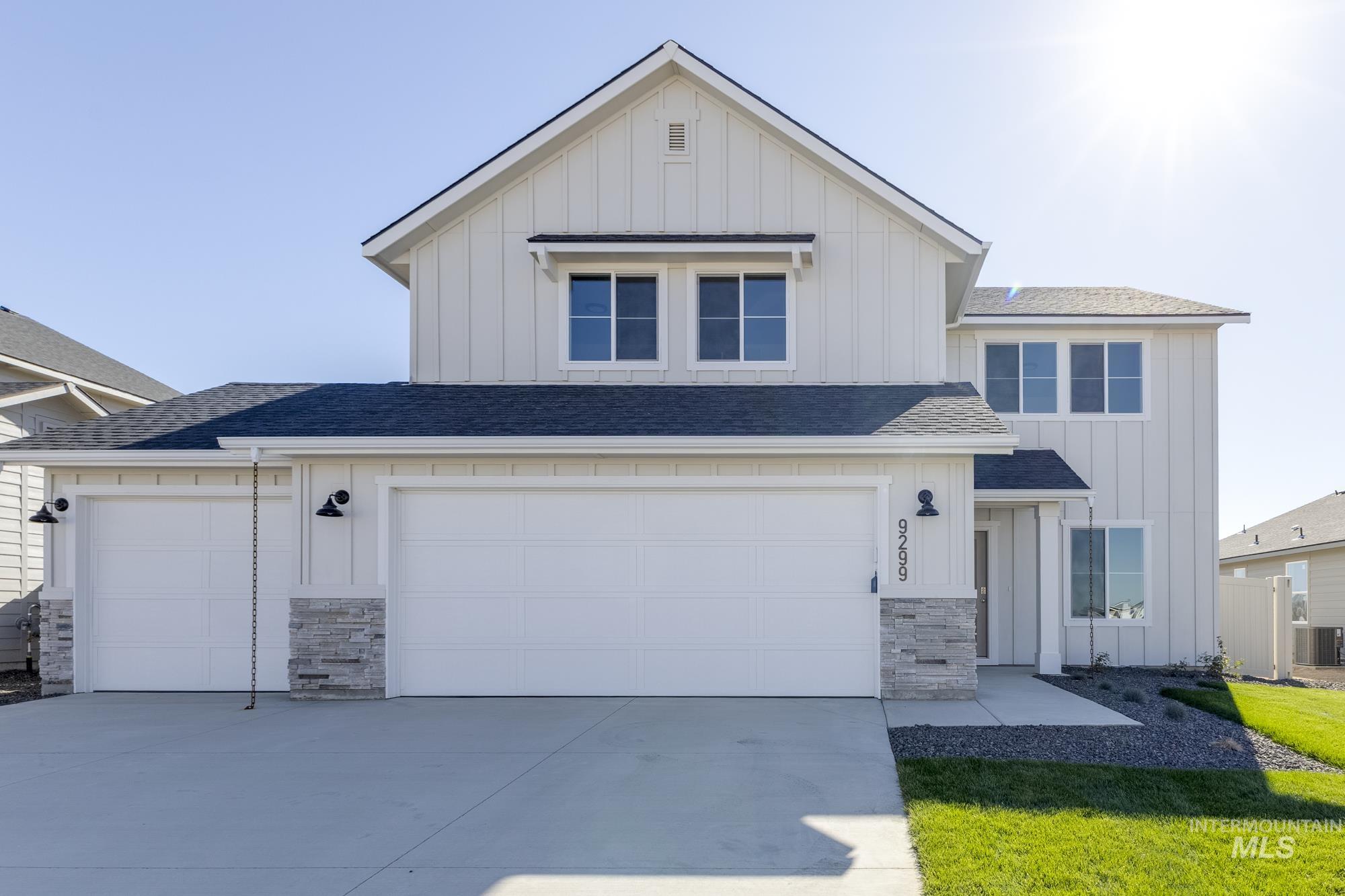 View of front of home featuring board and batten siding, stone siding, a shingled roof, driveway, and an attached garage