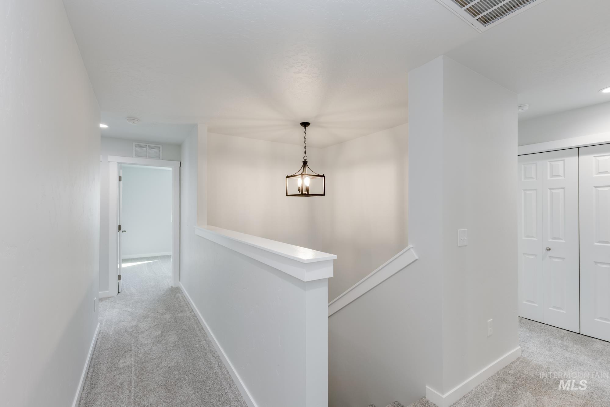 Hallway featuring light colored carpet, an upstairs landing, recessed lighting, and a chandelier