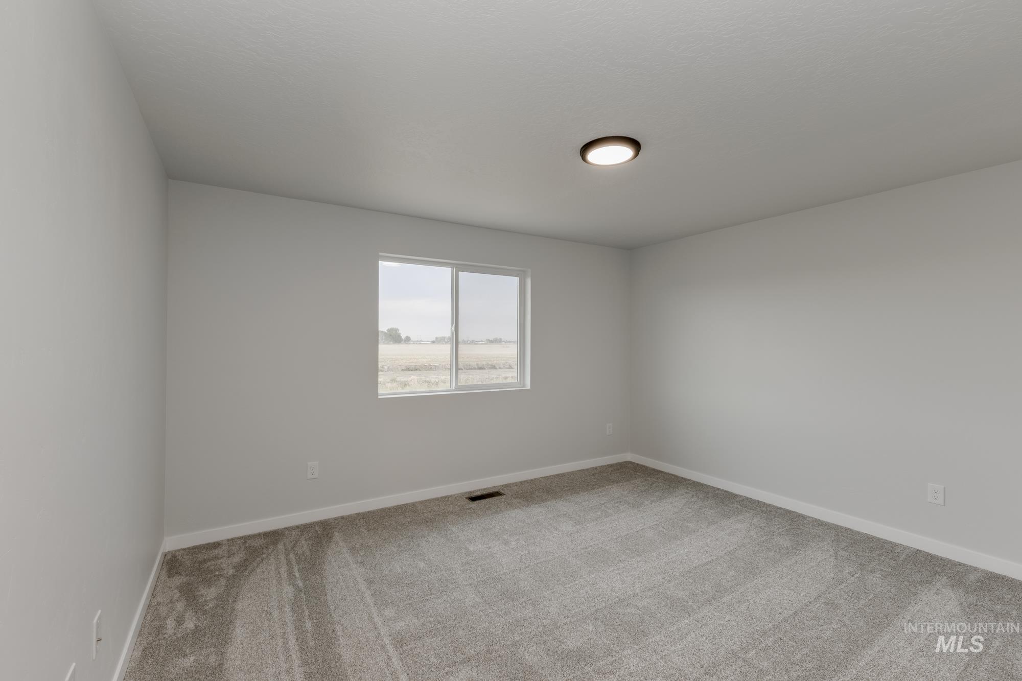 Spare room featuring light carpet and baseboards