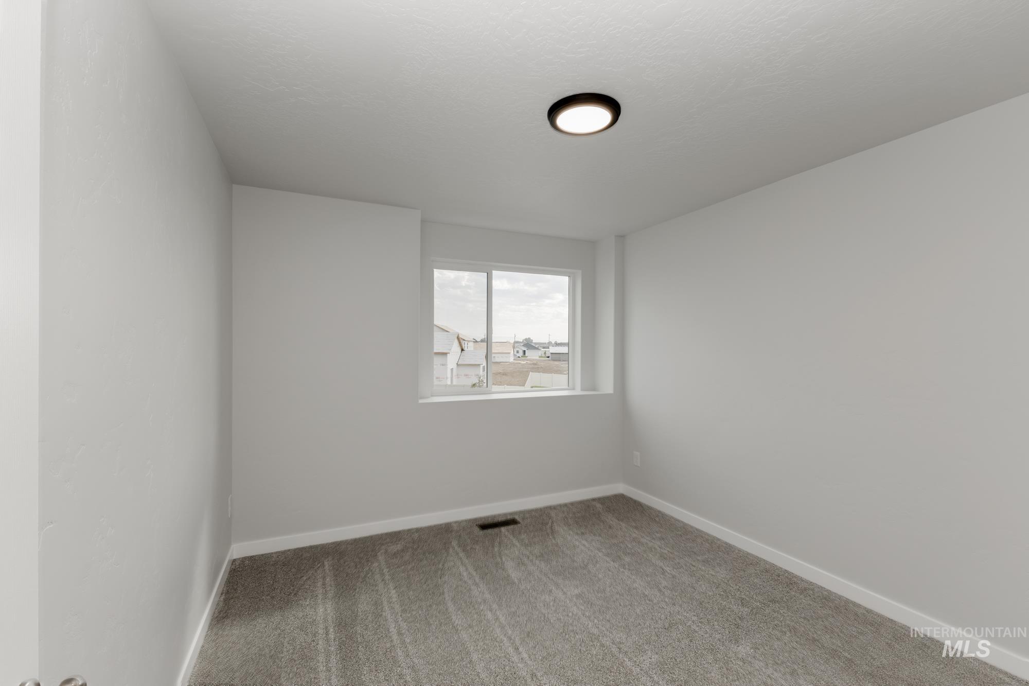 Spare room featuring carpet and baseboards