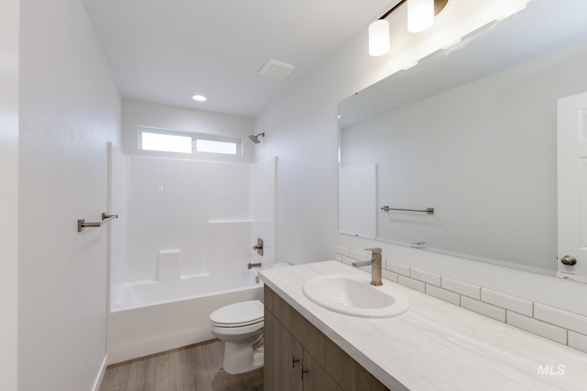Full bathroom featuring dark wood finished floors, washtub / shower combination, and vanity