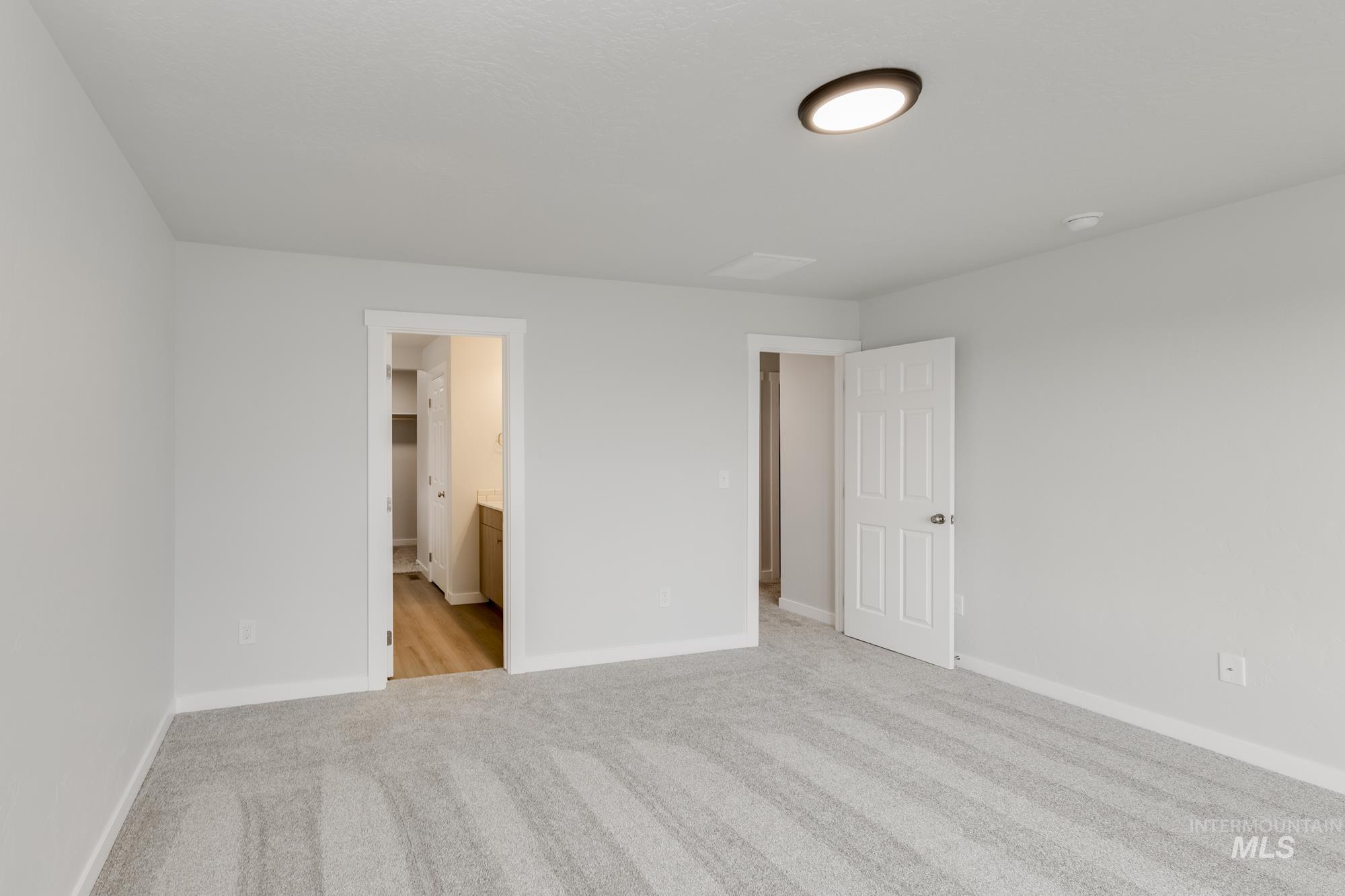 Unfurnished bedroom featuring light colored carpet and ensuite bathroom