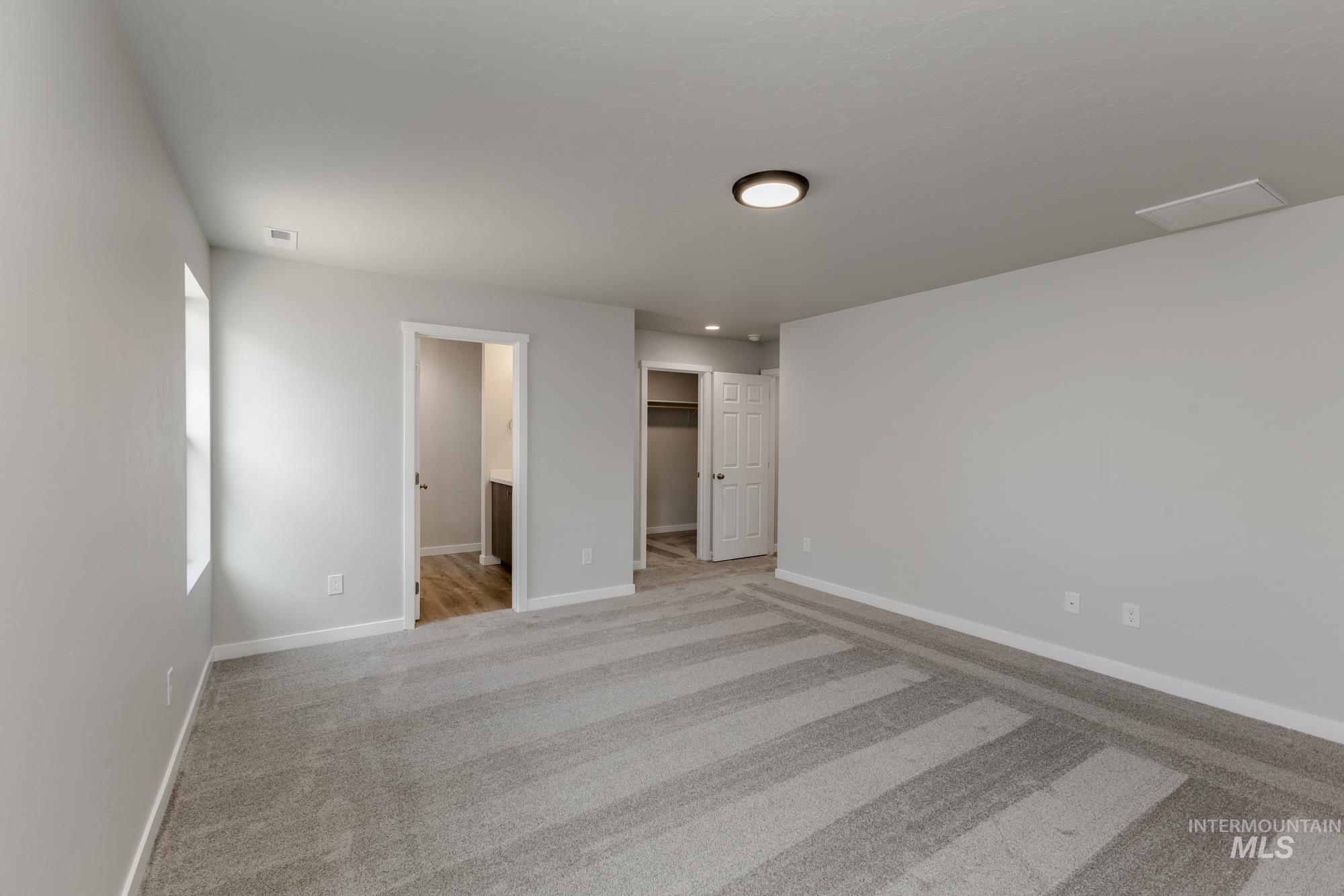 Unfurnished bedroom featuring a walk in closet, carpet floors, and ensuite bathroom