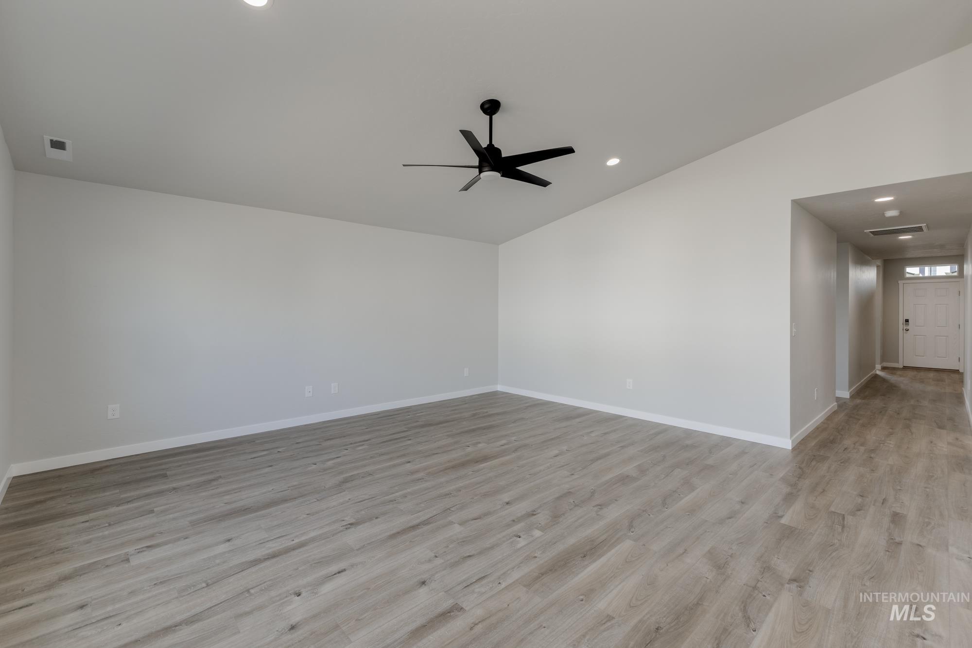 Spare room featuring light wood-style flooring, recessed lighting, a ceiling fan, and vaulted ceiling