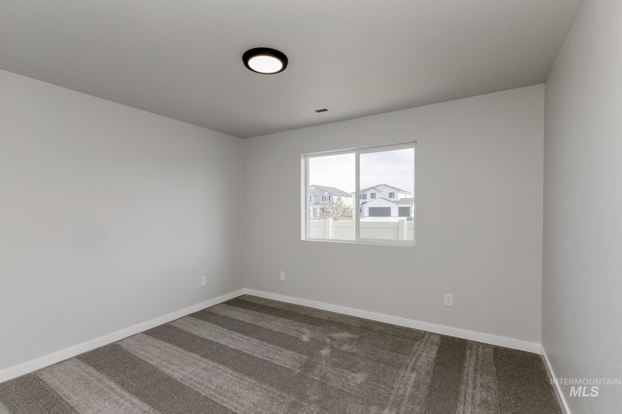 Carpeted spare room featuring baseboards
