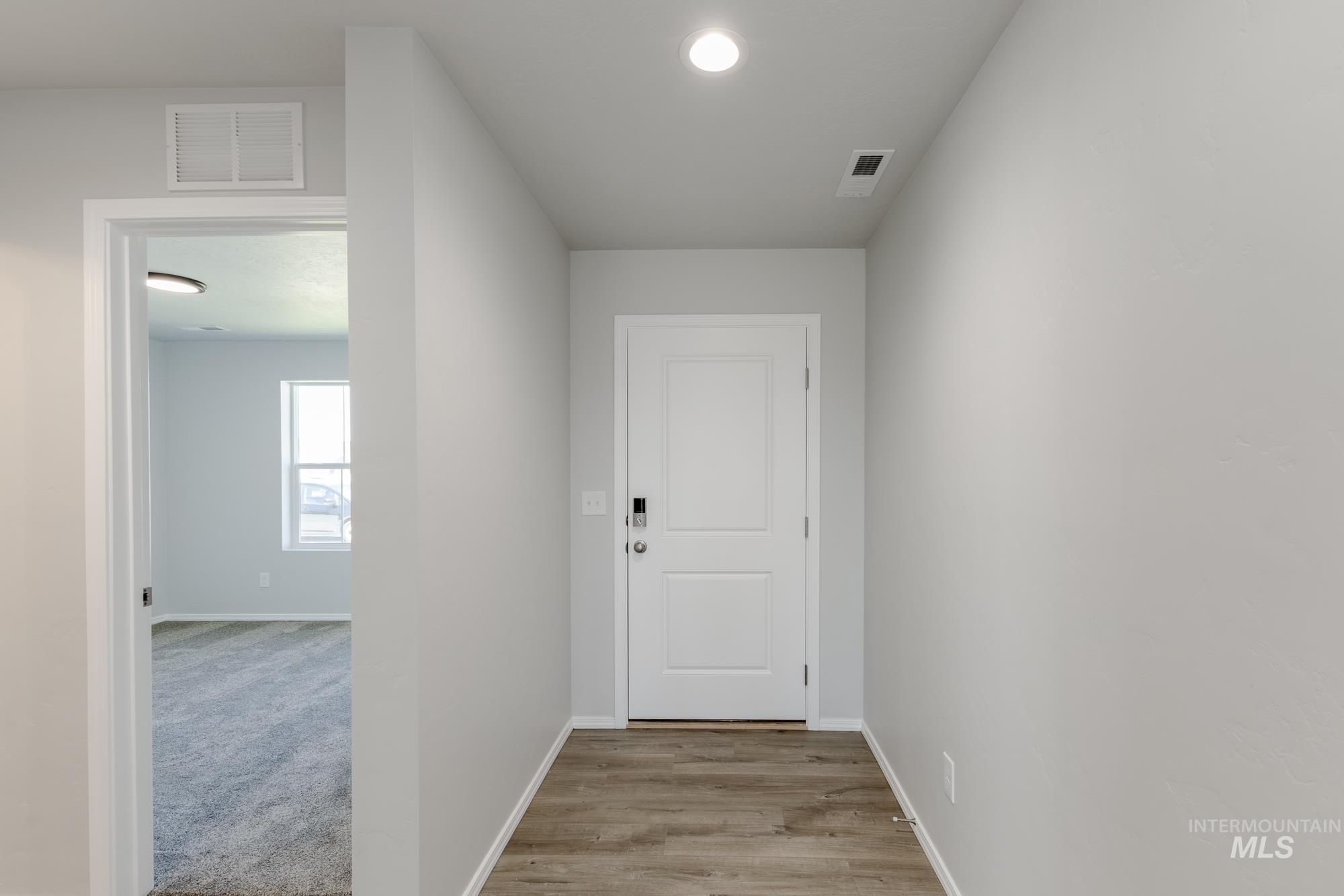 Hall with light wood finished floors and recessed lighting
