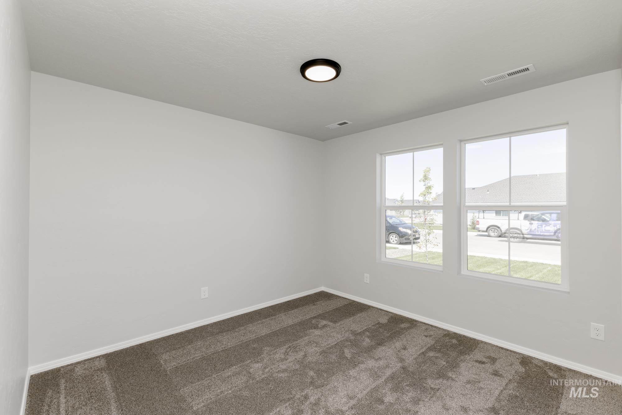 Unfurnished room featuring dark colored carpet and baseboards