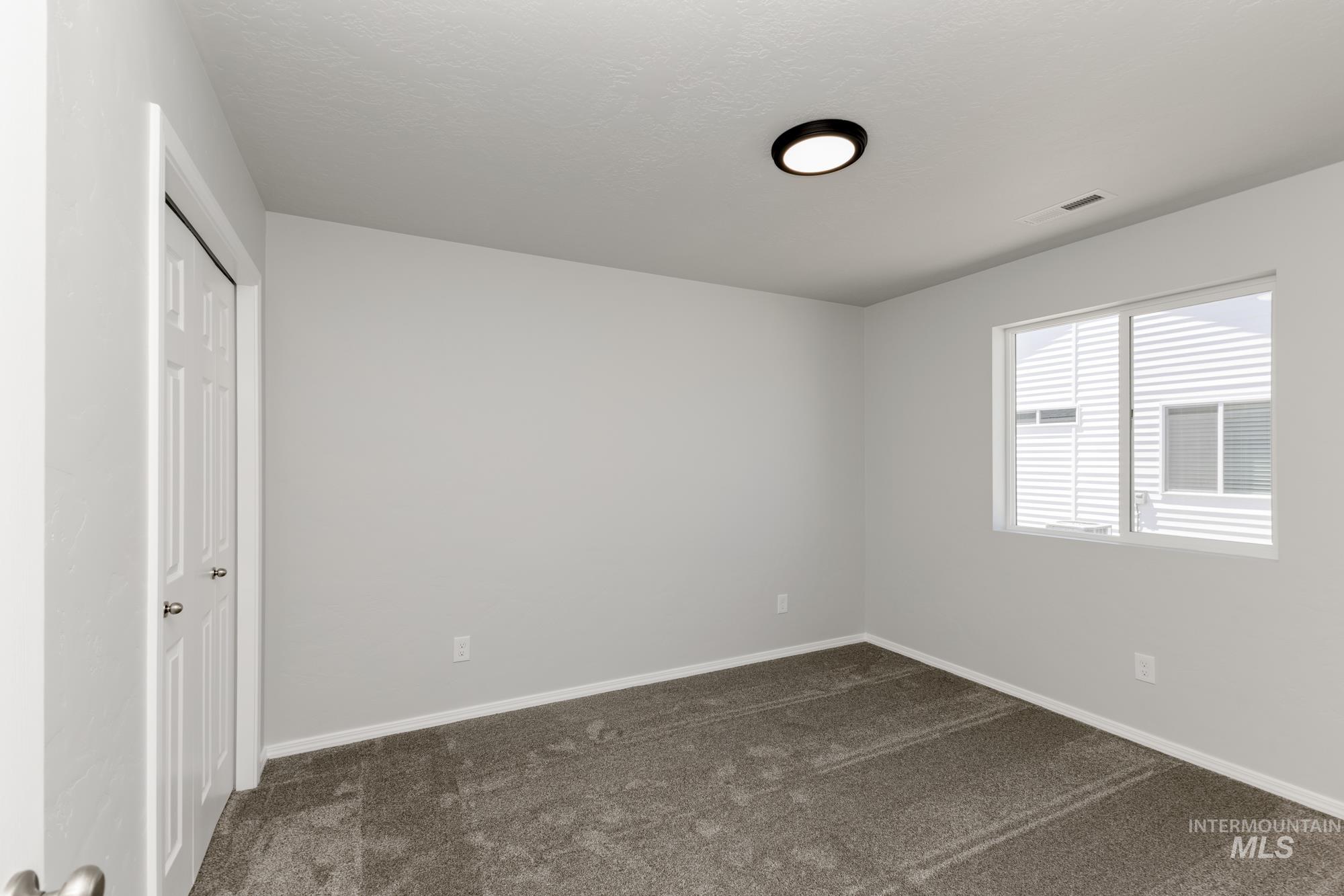 Unfurnished bedroom with a closet and dark colored carpet