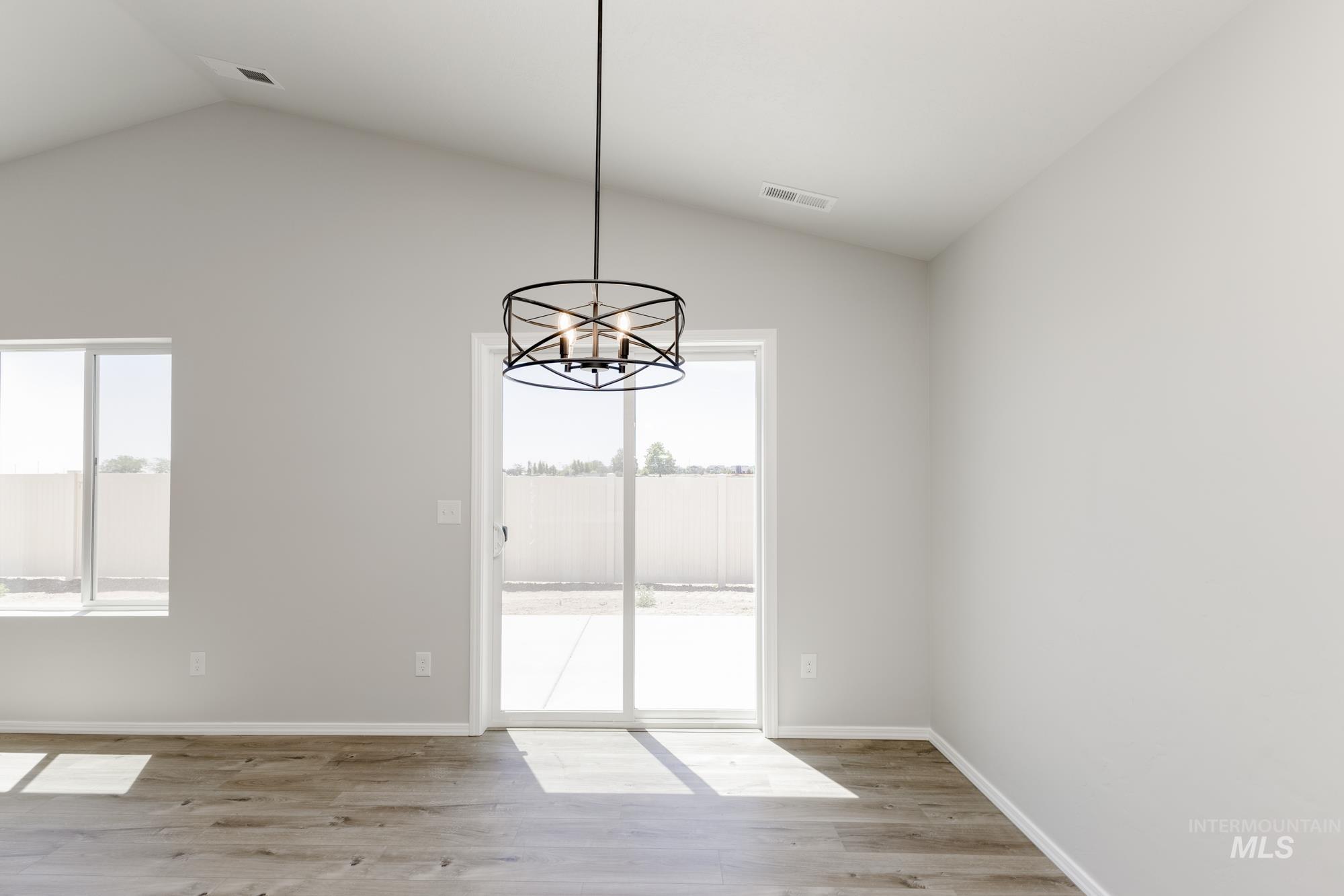 Unfurnished dining area featuring lofted ceiling, light wood-style floors, and a chandelier
