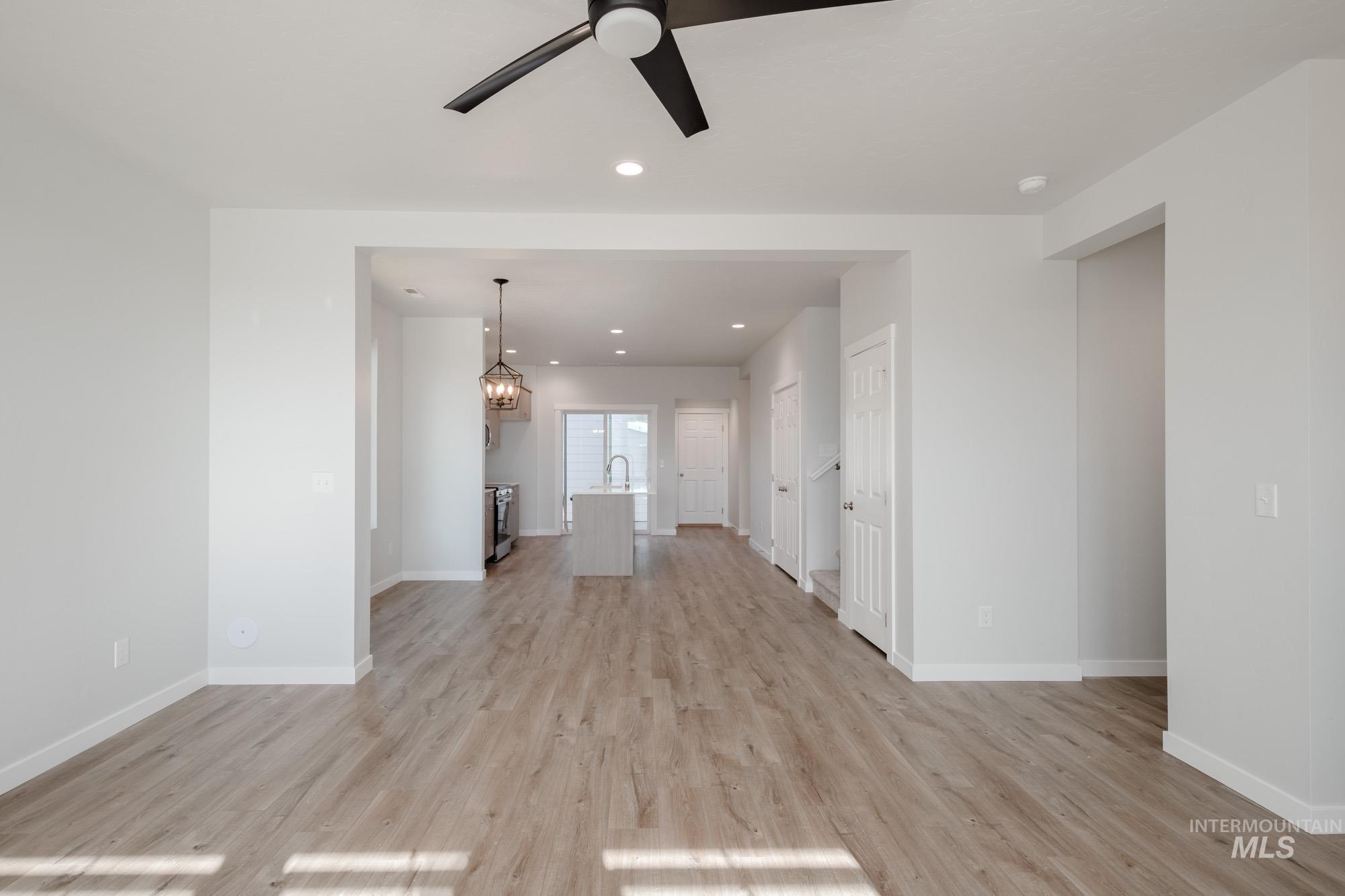 Unfurnished living room with recessed lighting, a chandelier, light wood finished floors, and a ceiling fan