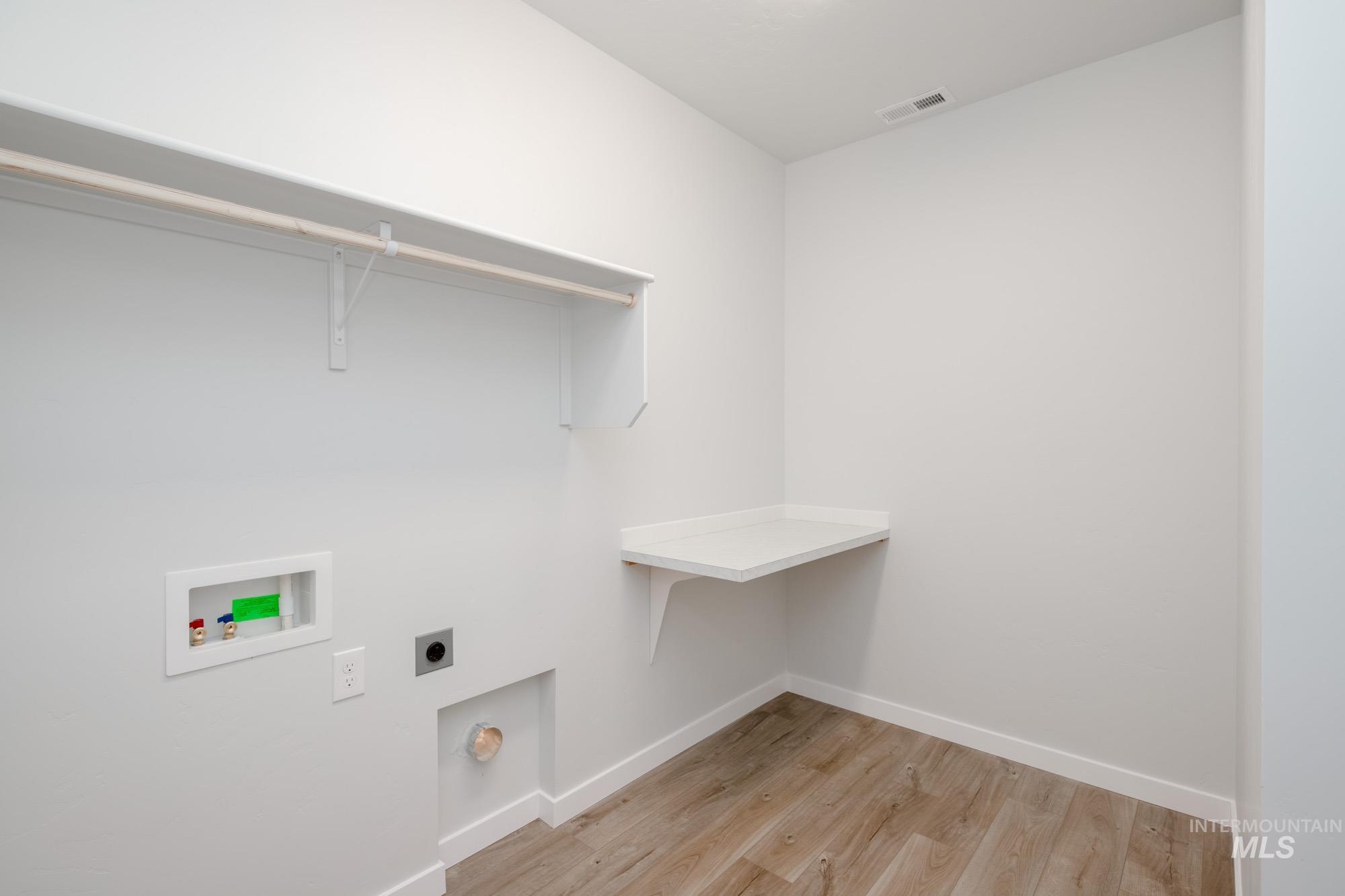Washroom with light wood-style floors, hookup for a washing machine, and electric dryer hookup