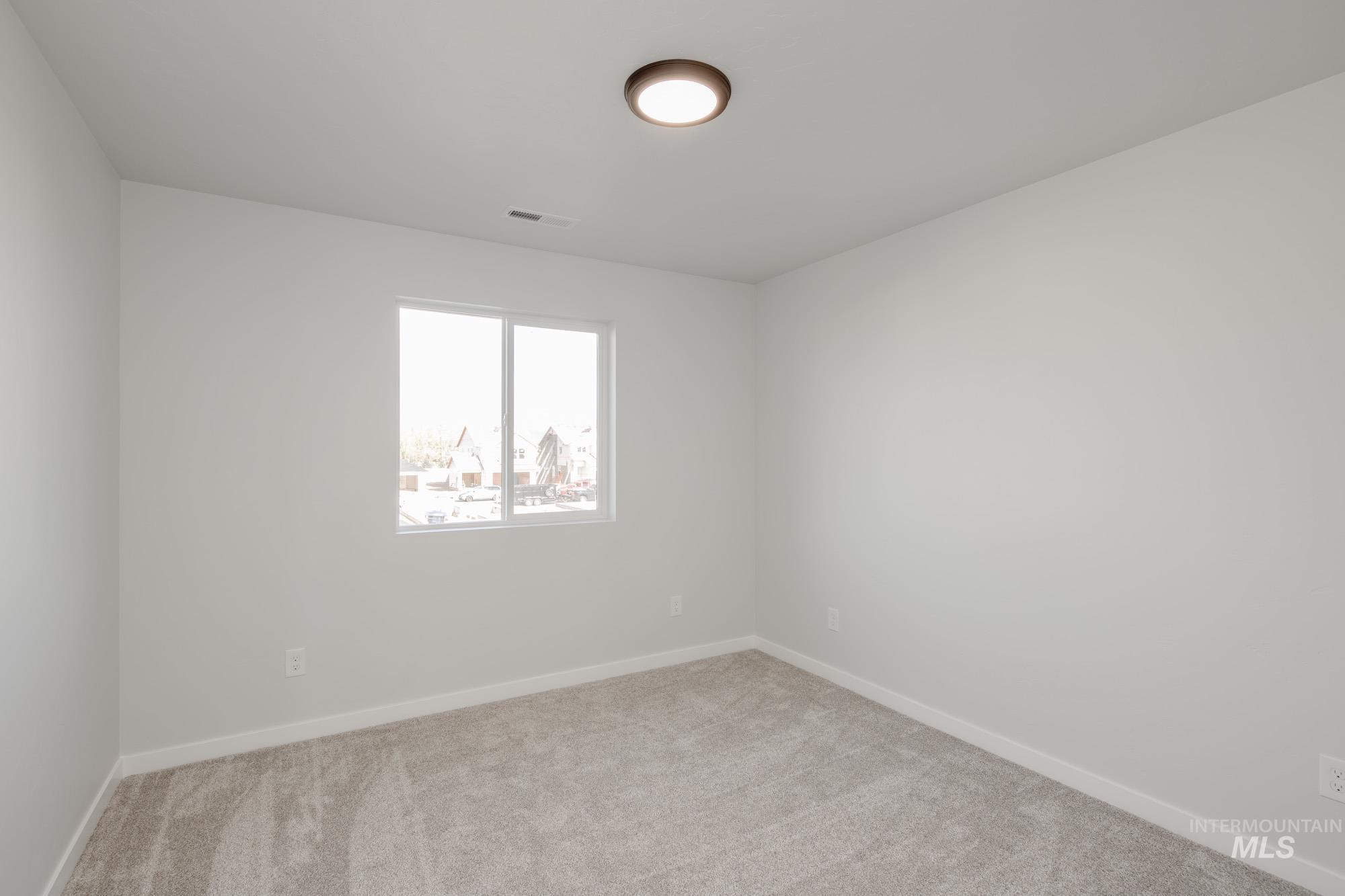 Carpeted spare room featuring baseboards