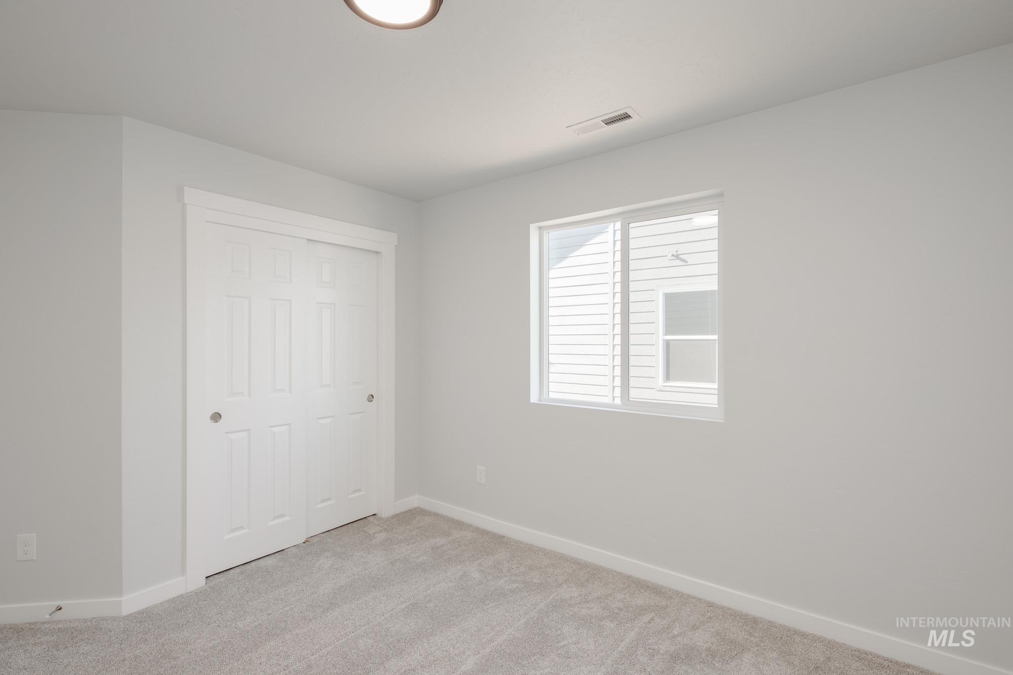 Unfurnished bedroom featuring light carpet and a closet