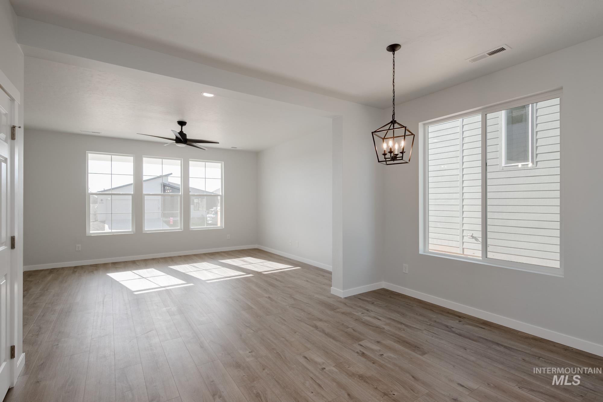 Spare room with light wood-style floors, ceiling fan, a chandelier, and recessed lighting