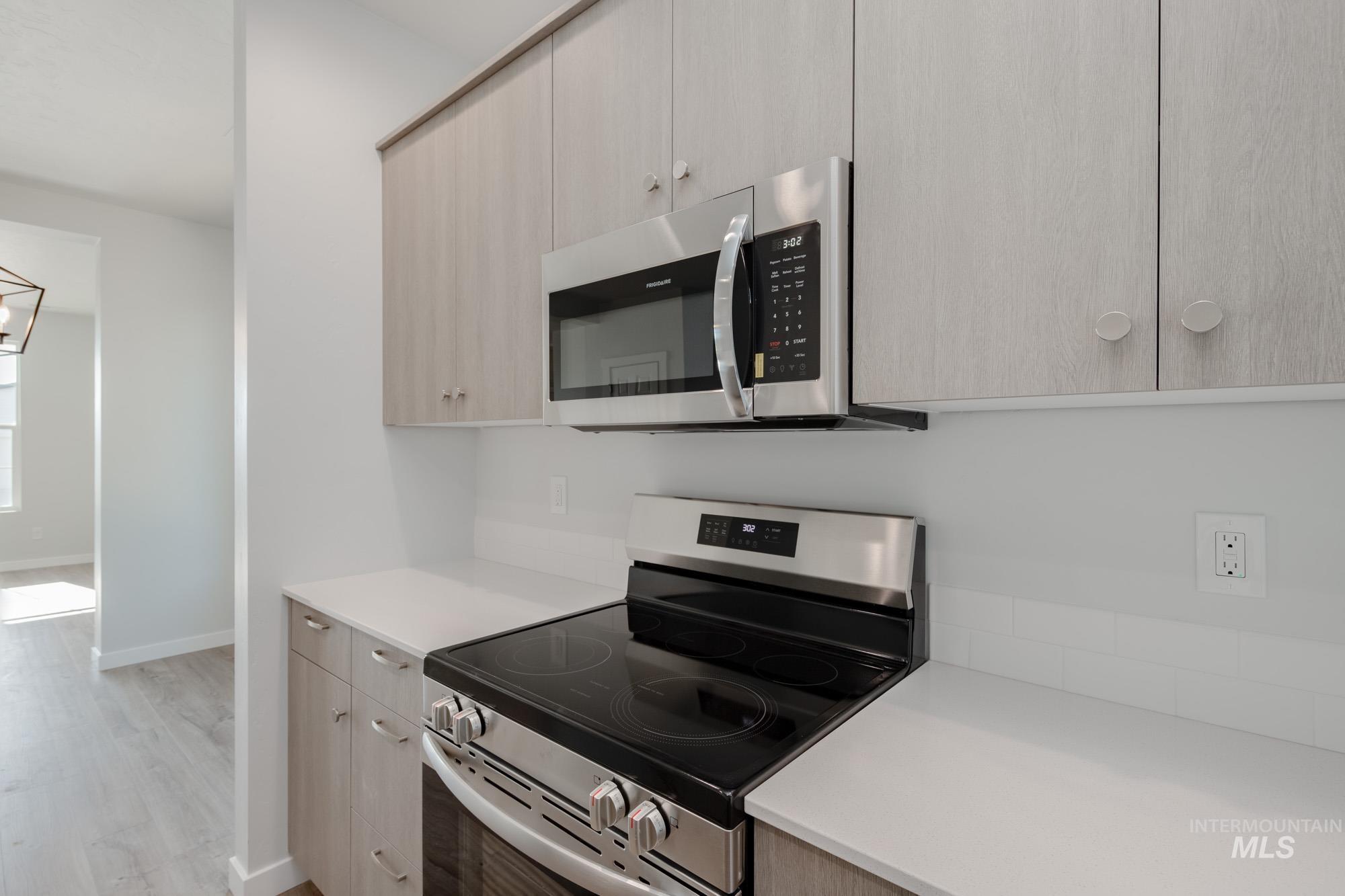 Kitchen with appliances with stainless steel finishes, light wood-style floors, modern cabinets, and light brown cabinets
