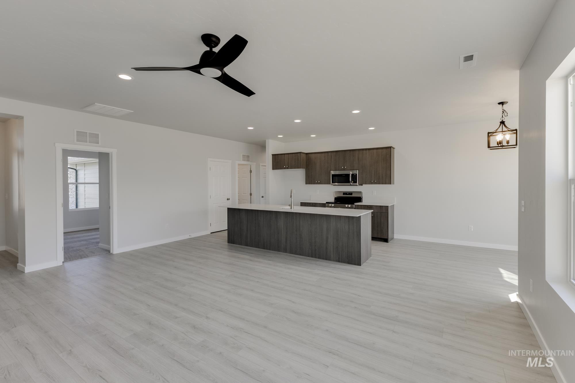 Kitchen with open floor plan, light countertops, dark brown cabinets, light wood-type flooring, and recessed lighting