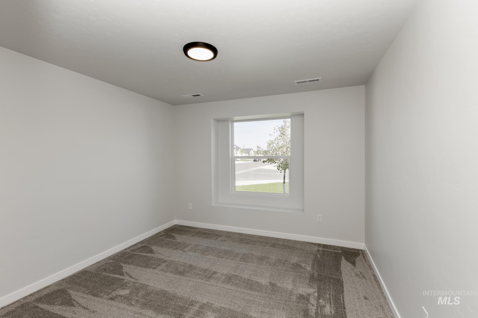 Carpeted spare room featuring baseboards