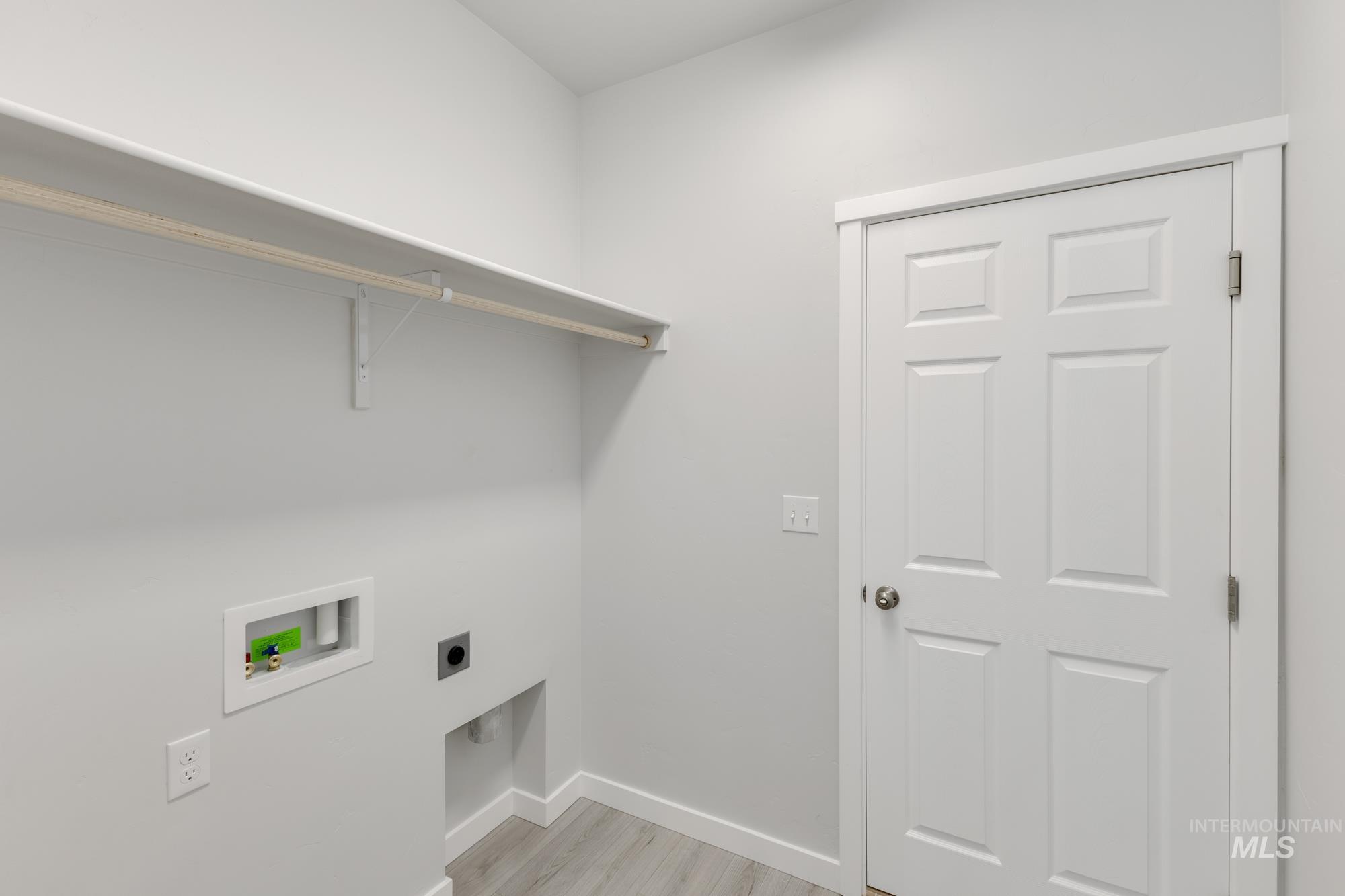 Washroom featuring light wood-type flooring, hookup for an electric dryer, and hookup for a washing machine