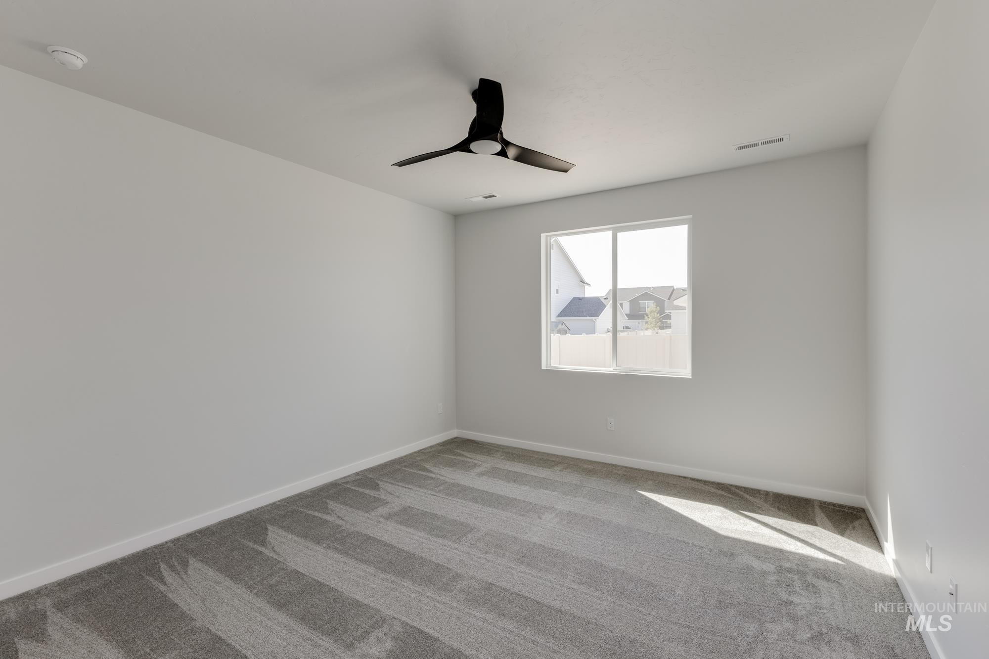 Empty room featuring carpet floors and a ceiling fan