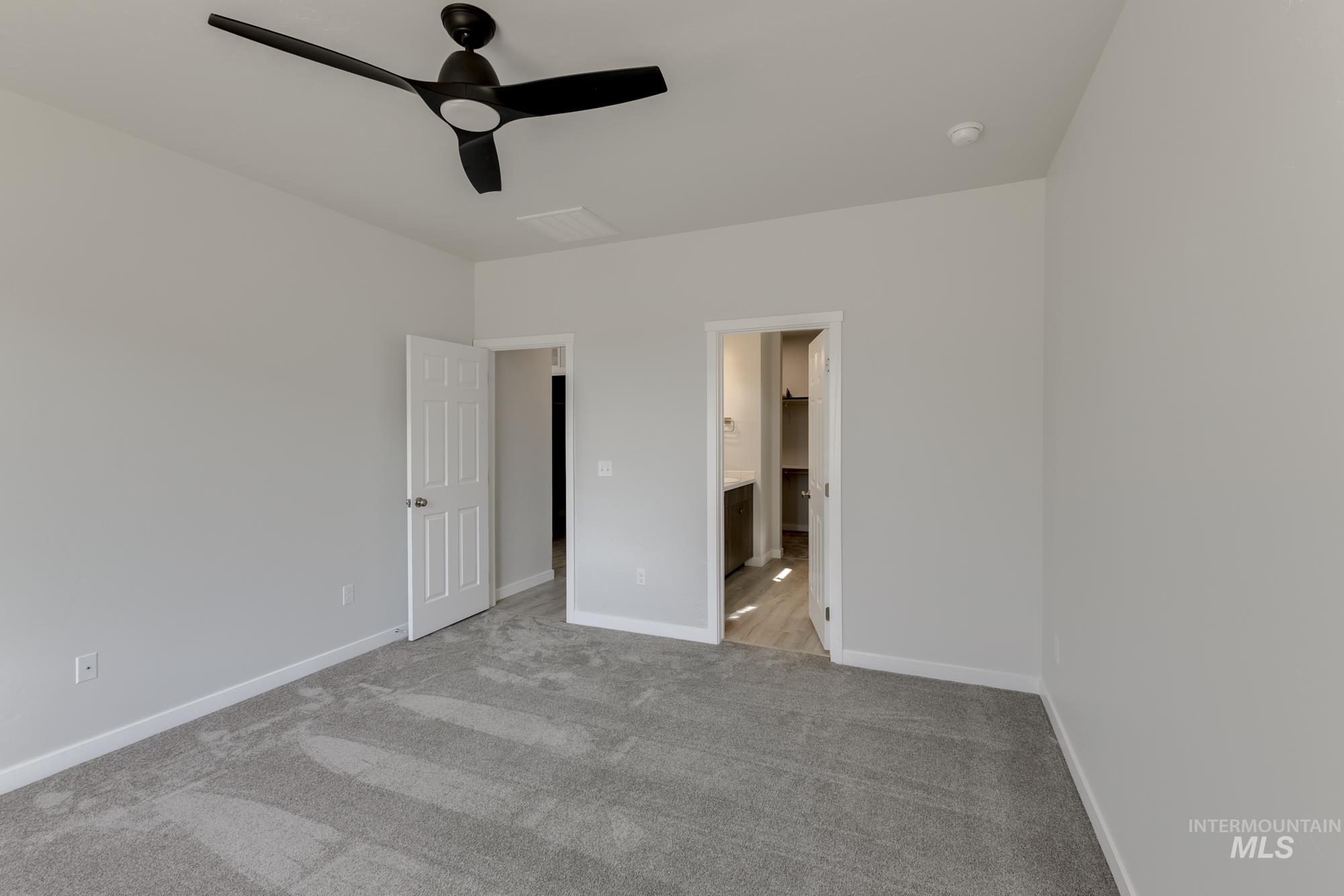 Unfurnished bedroom featuring light colored carpet, a ceiling fan, and connected bathroom