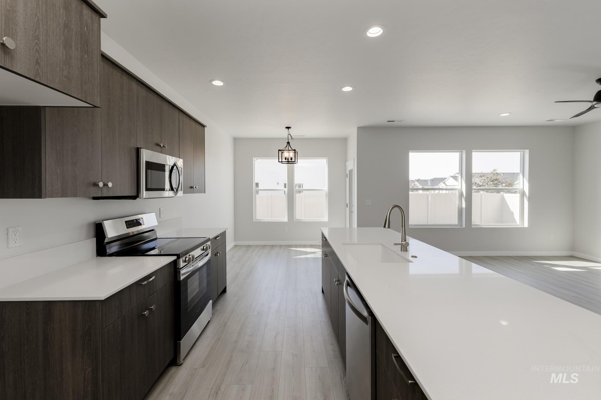 Kitchen featuring stainless steel appliances, light wood finished floors, dark brown cabinetry, modern cabinets, and recessed lighting