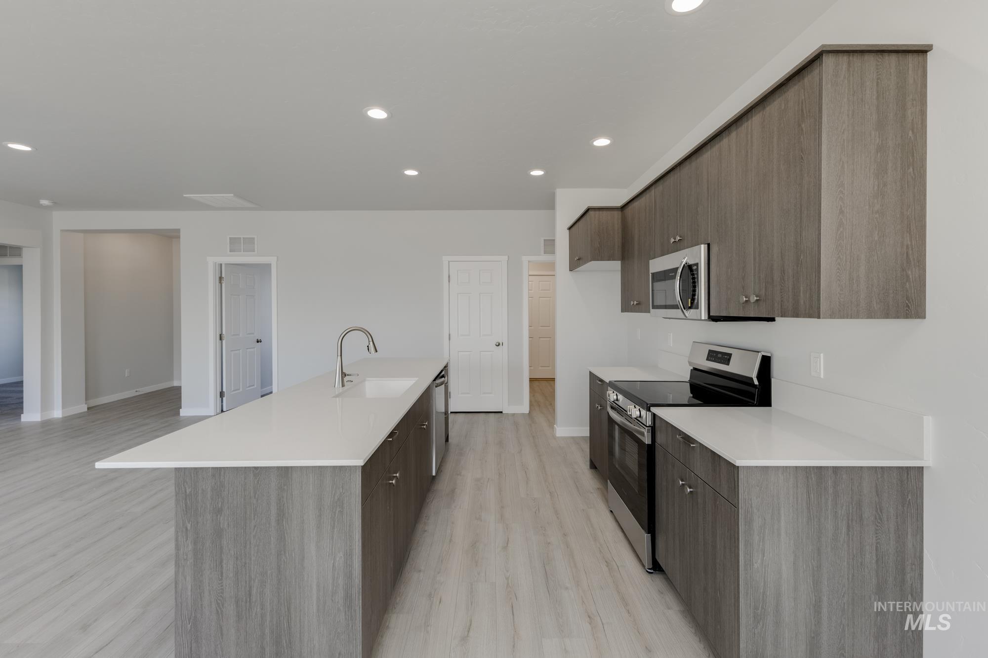 Kitchen with modern cabinets, stainless steel appliances, recessed lighting, and light wood-style floors