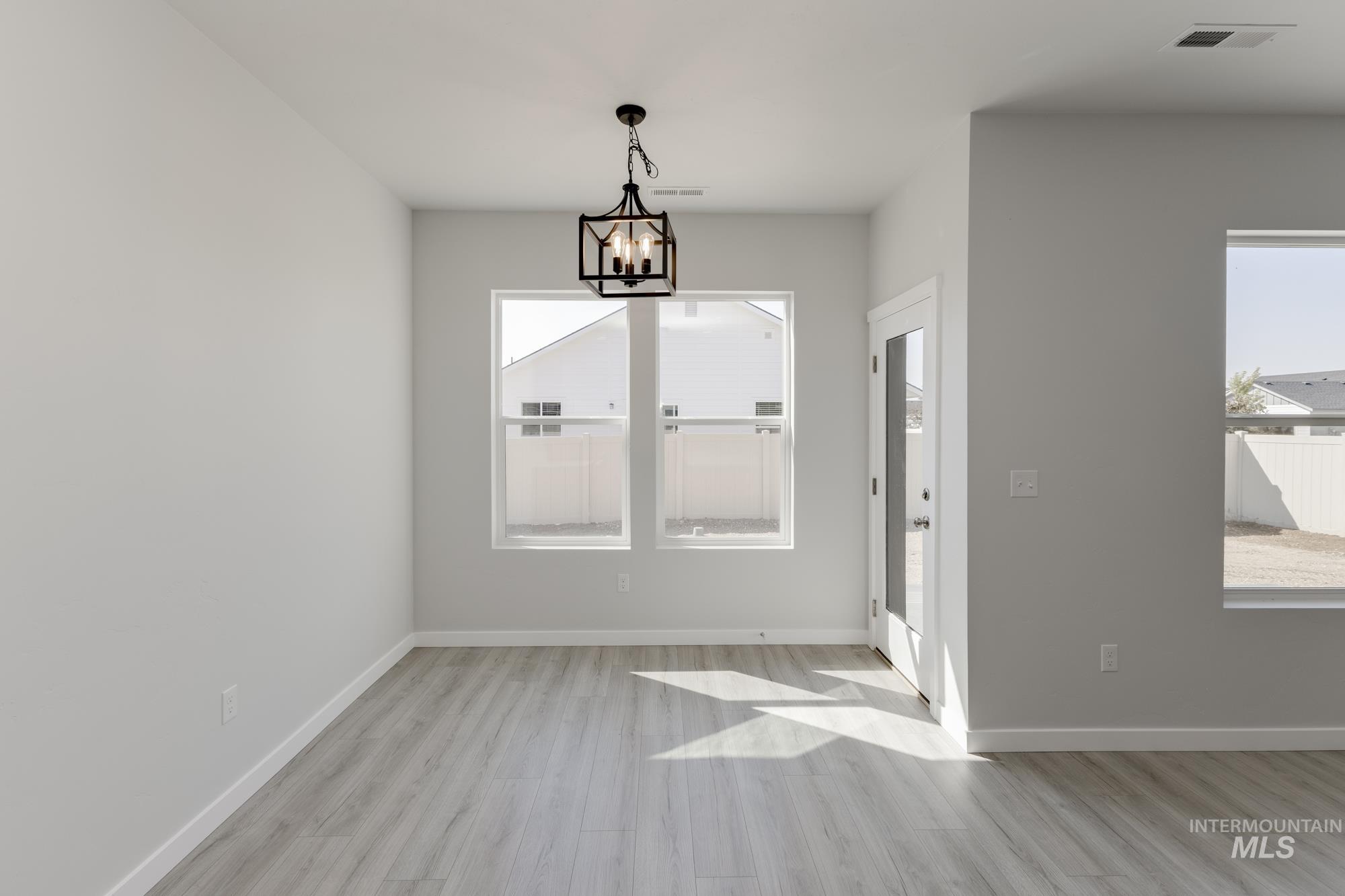 Unfurnished dining area featuring light wood finished floors and a chandelier