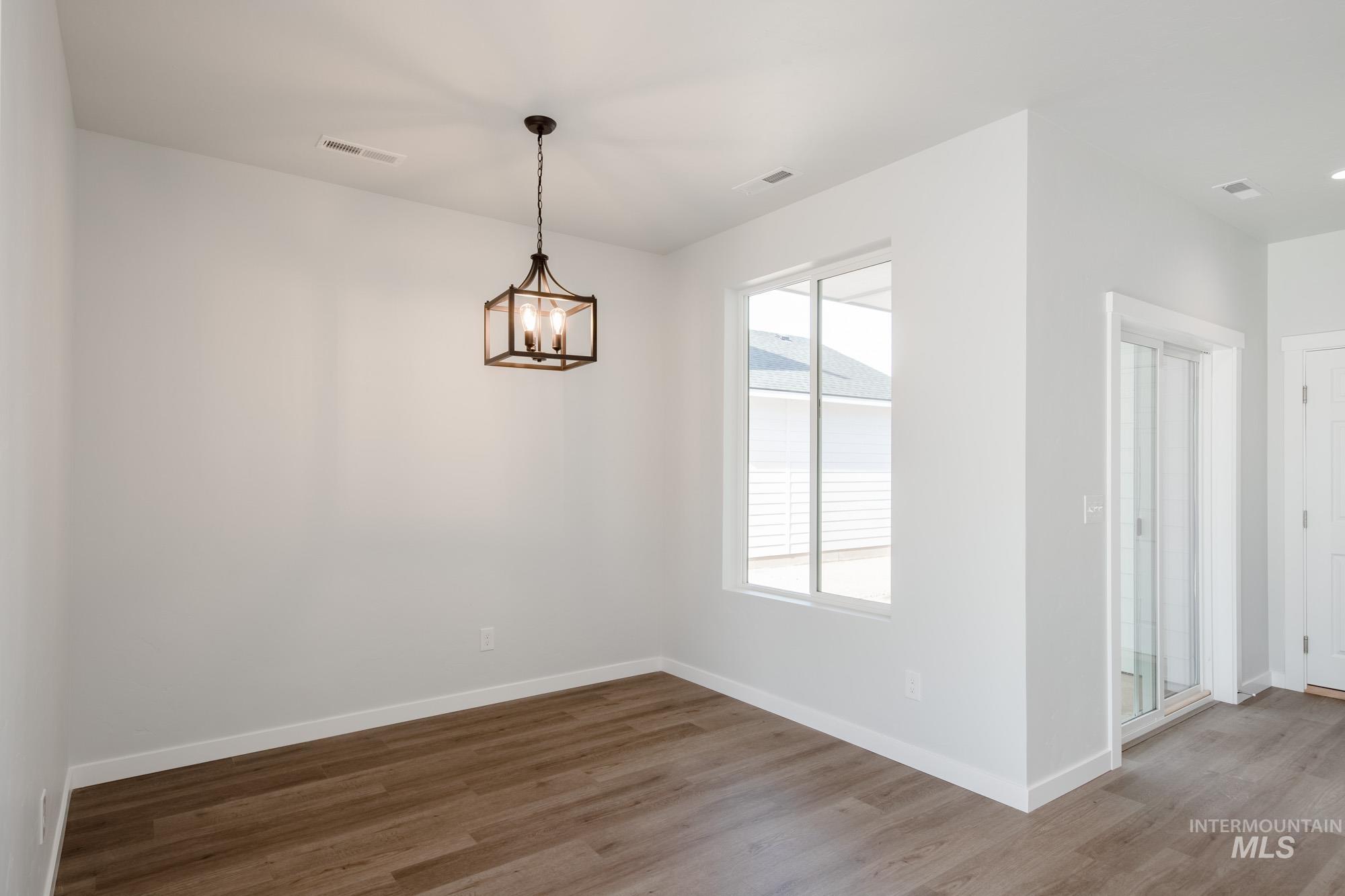Unfurnished dining area with wood finished floors and a chandelier