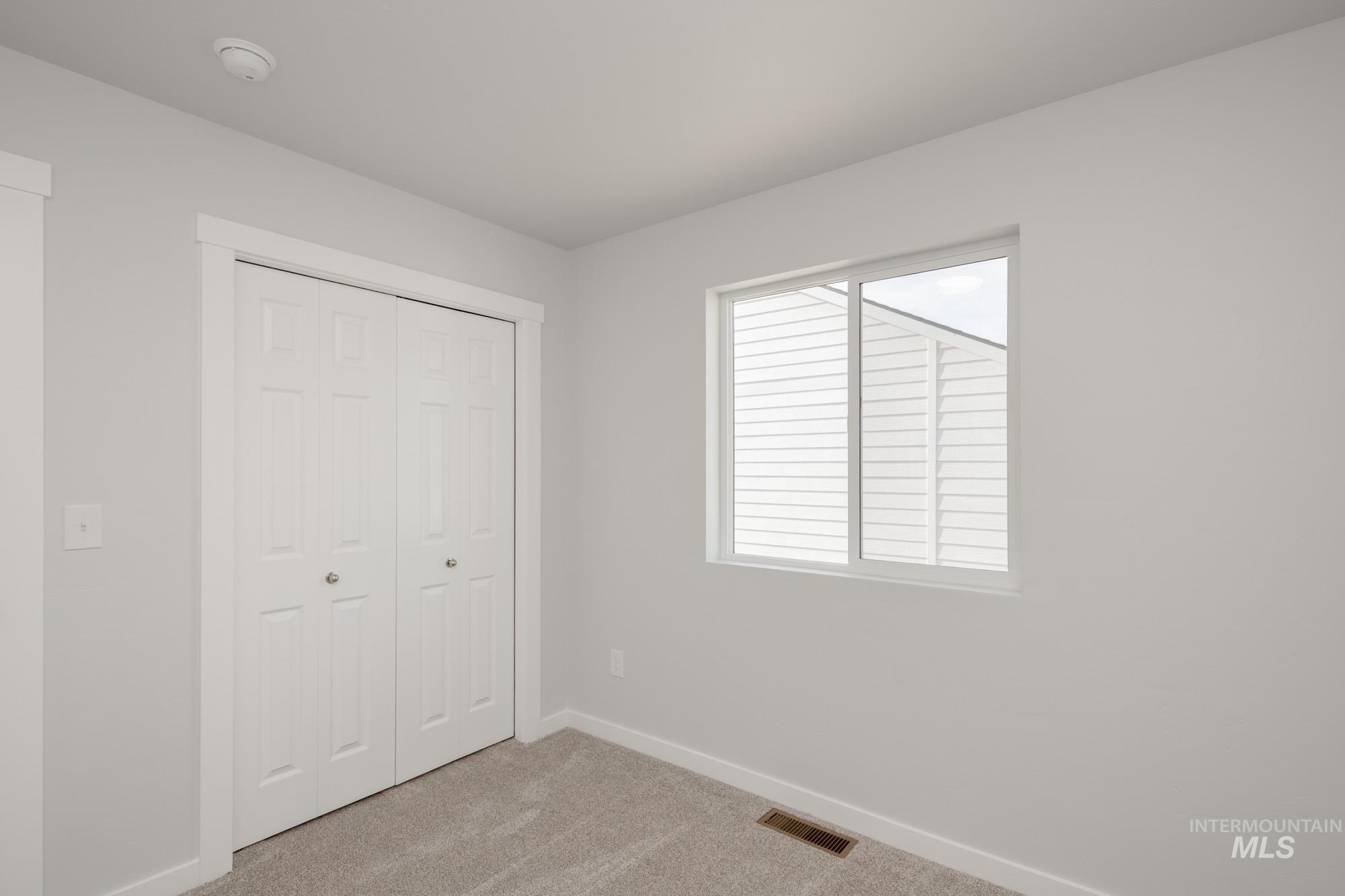 Unfurnished bedroom with light colored carpet and a closet