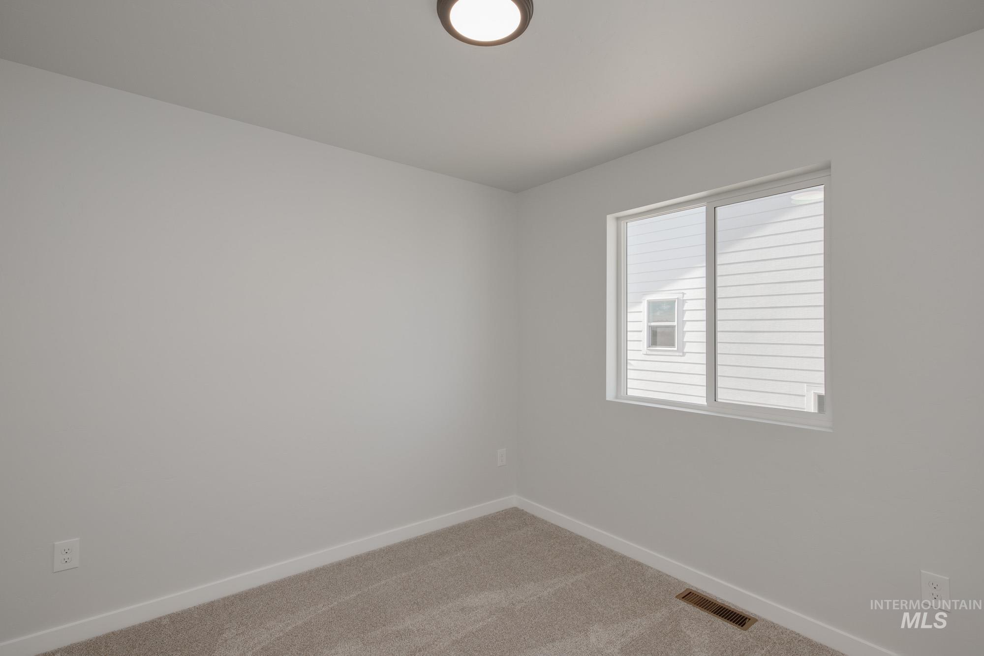 Spare room with baseboards and light carpet