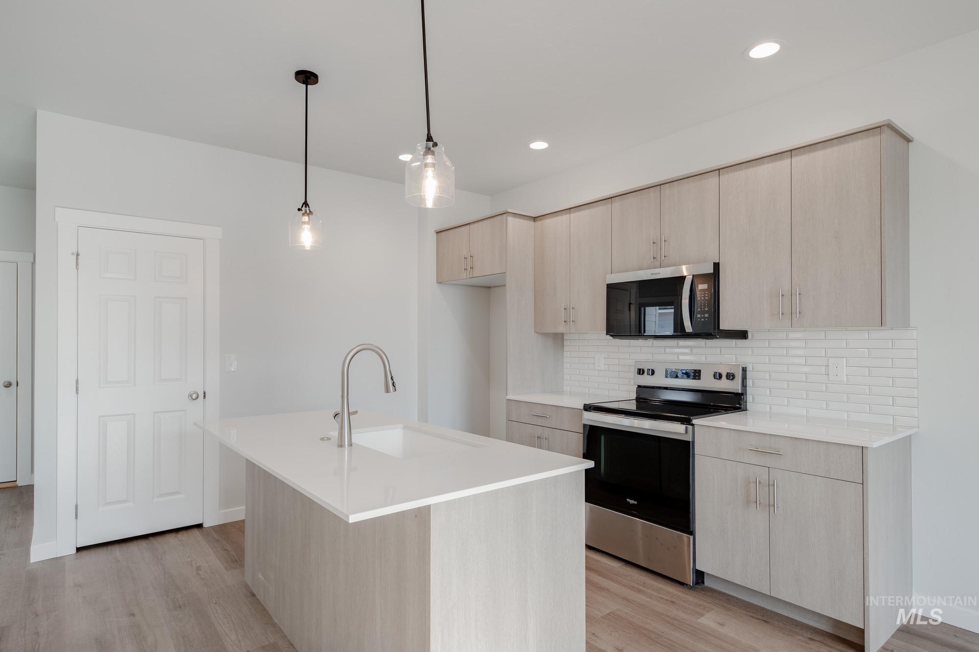 Kitchen featuring light brown cabinets, stainless steel appliances, and recessed lighting
