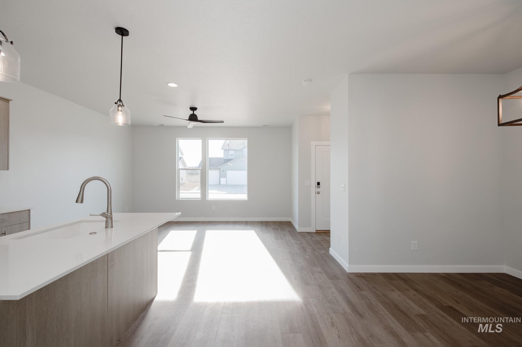 Kitchen featuring pendant lighting, light wood-style flooring, ceiling fan, light stone countertops, and open floor plan