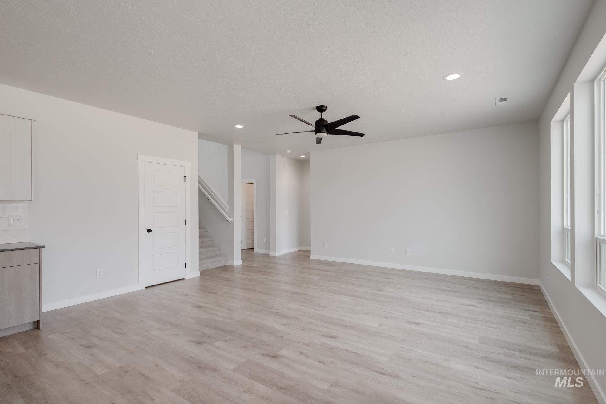 Unfurnished living room with recessed lighting, light wood-type flooring, stairway, and ceiling fan