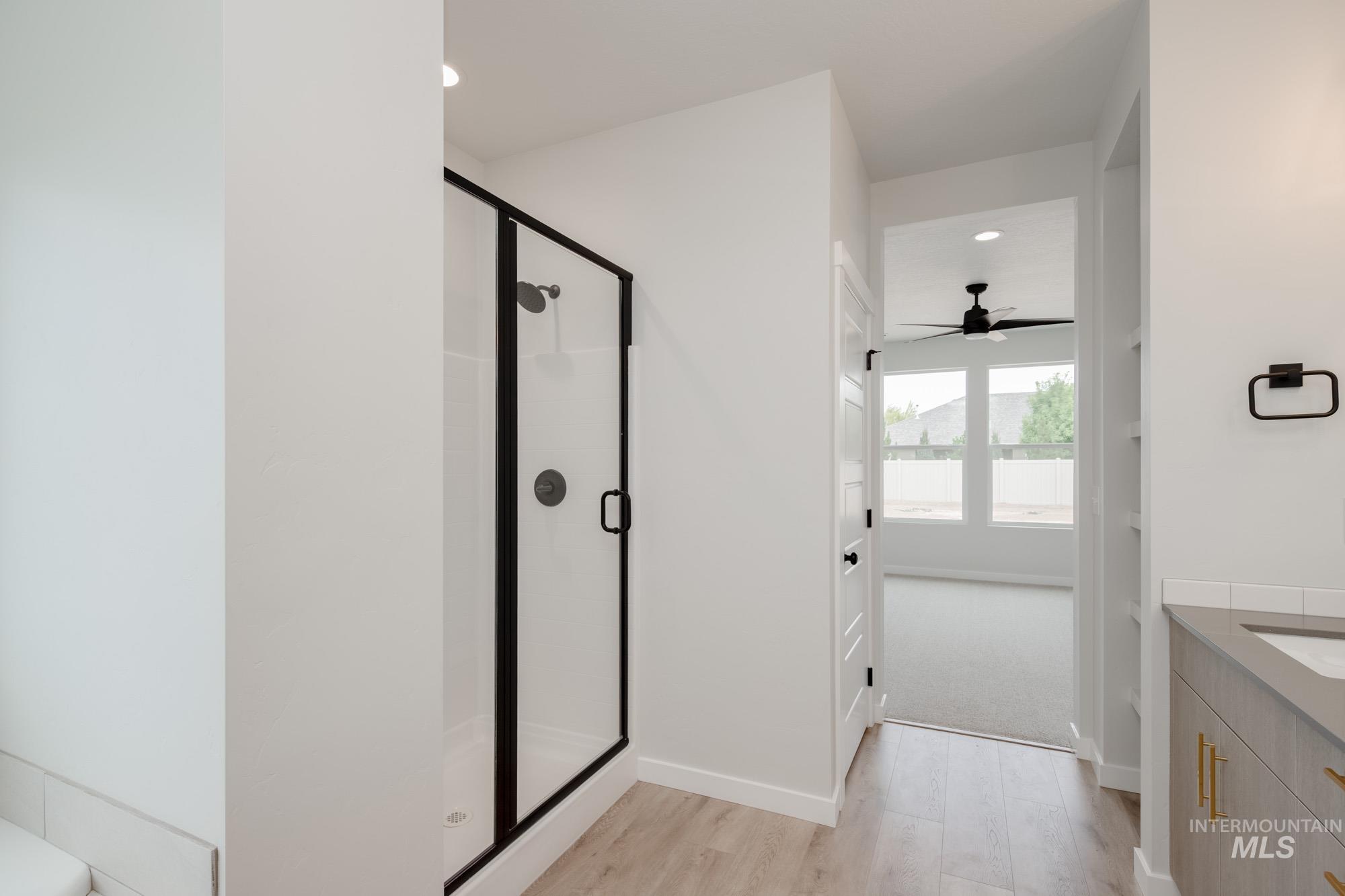 Bathroom featuring vanity, light wood-type flooring, a stall shower, recessed lighting, and ceiling fan