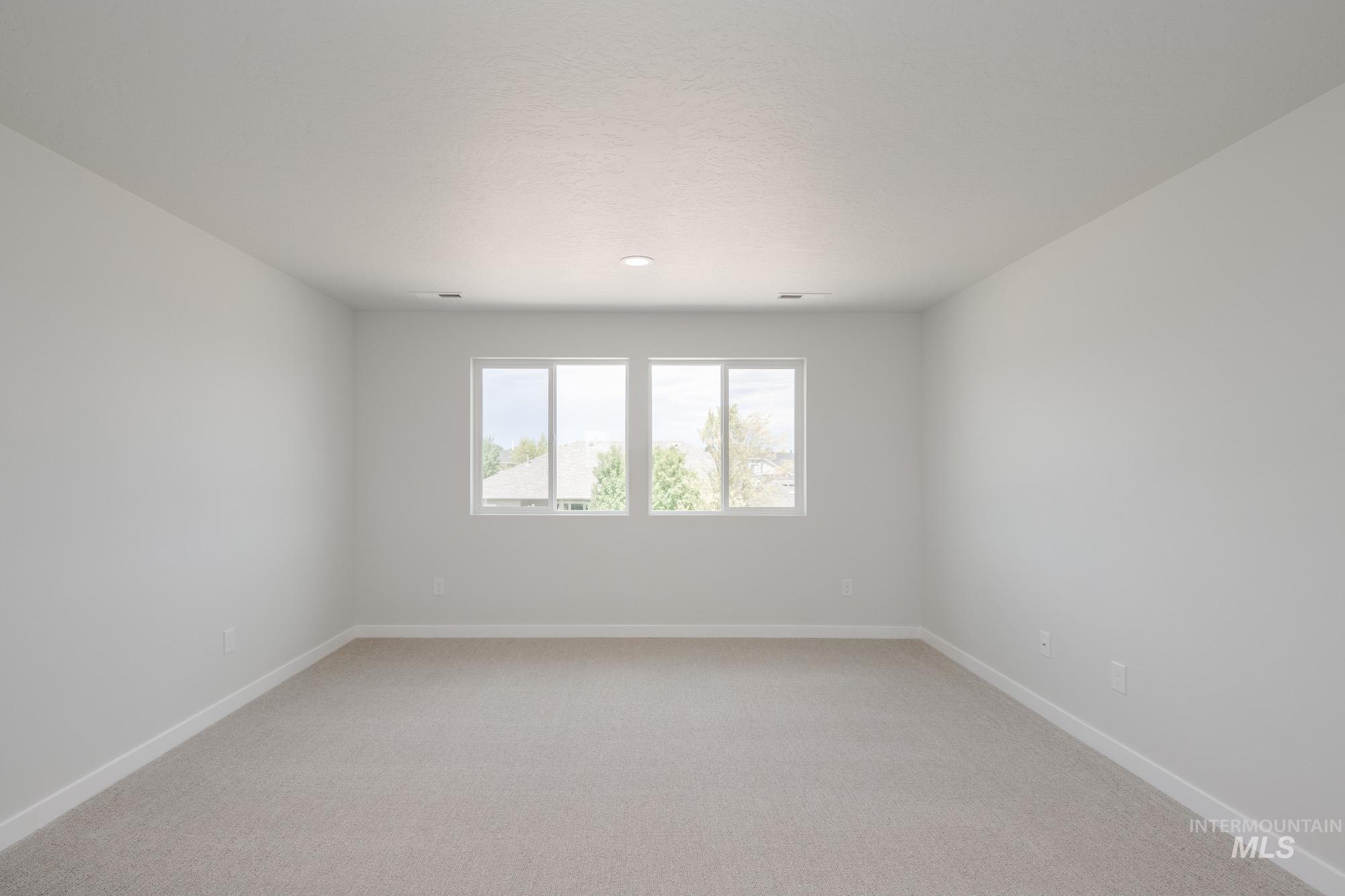 Spare room featuring light carpet and baseboards