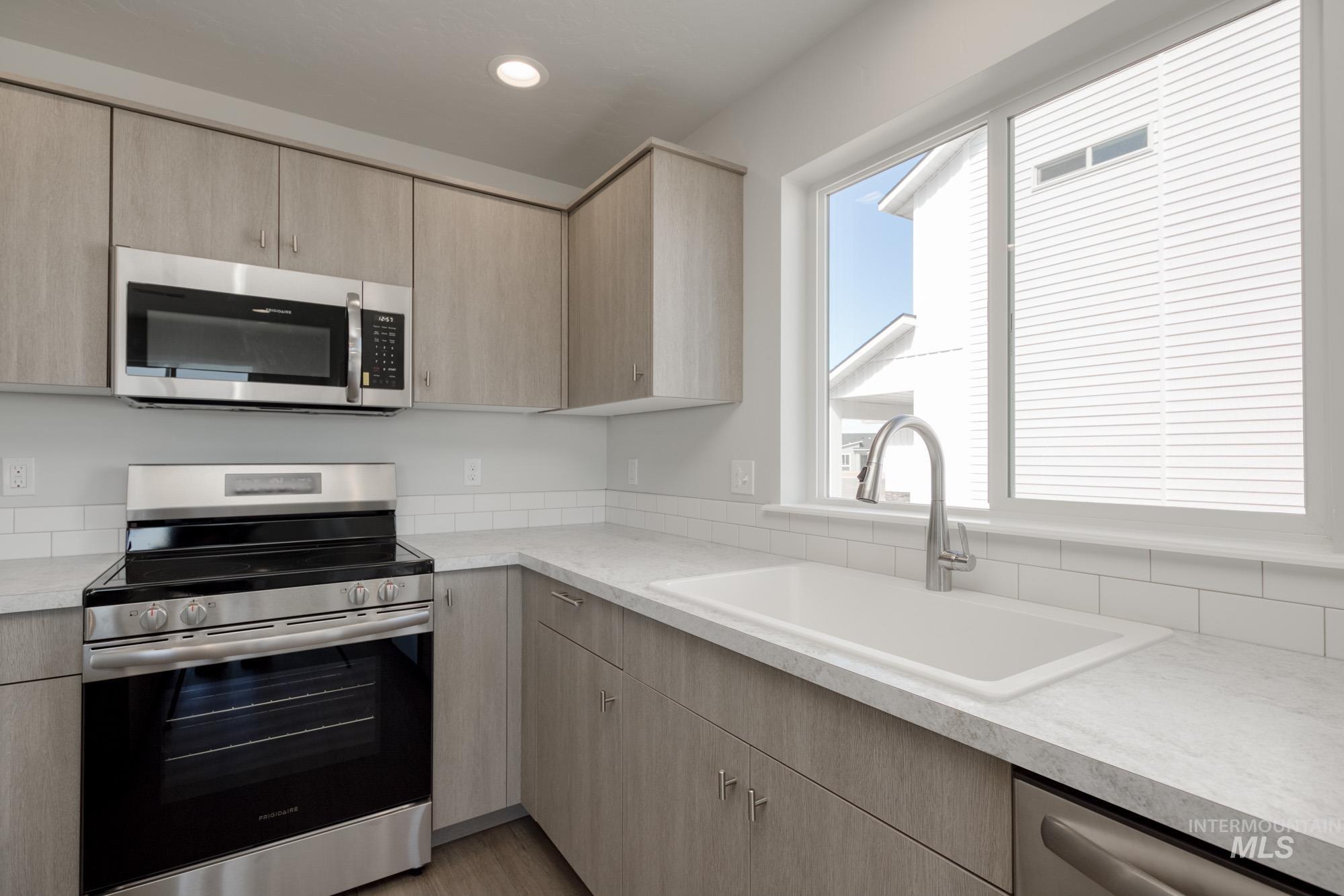 Kitchen with stainless steel appliances, light brown cabinets, and light countertops