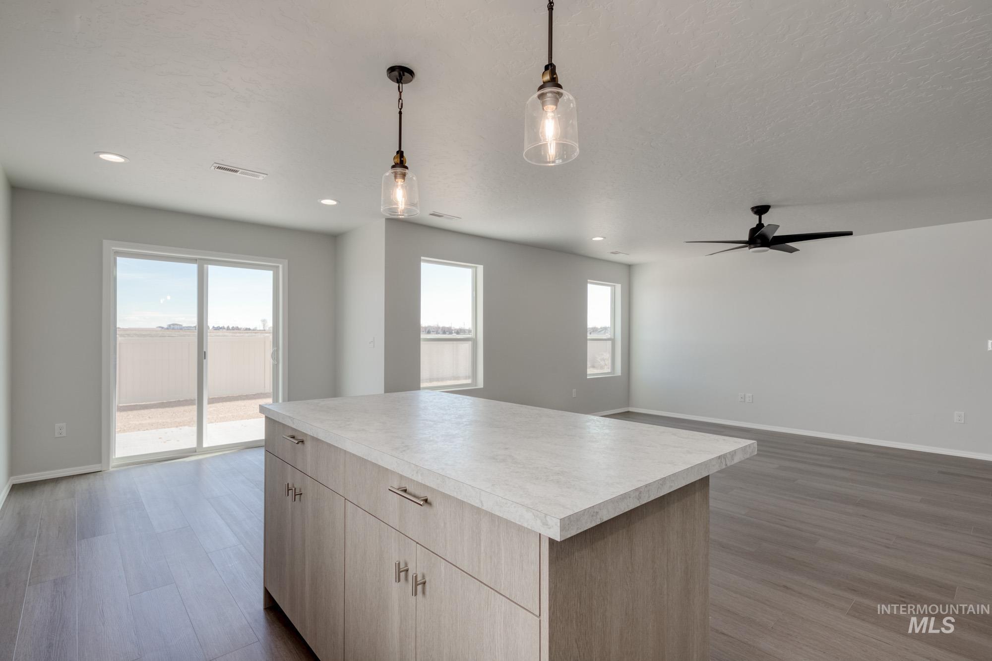 Kitchen with open floor plan, dark wood-style floors, light countertops, and pendant lighting