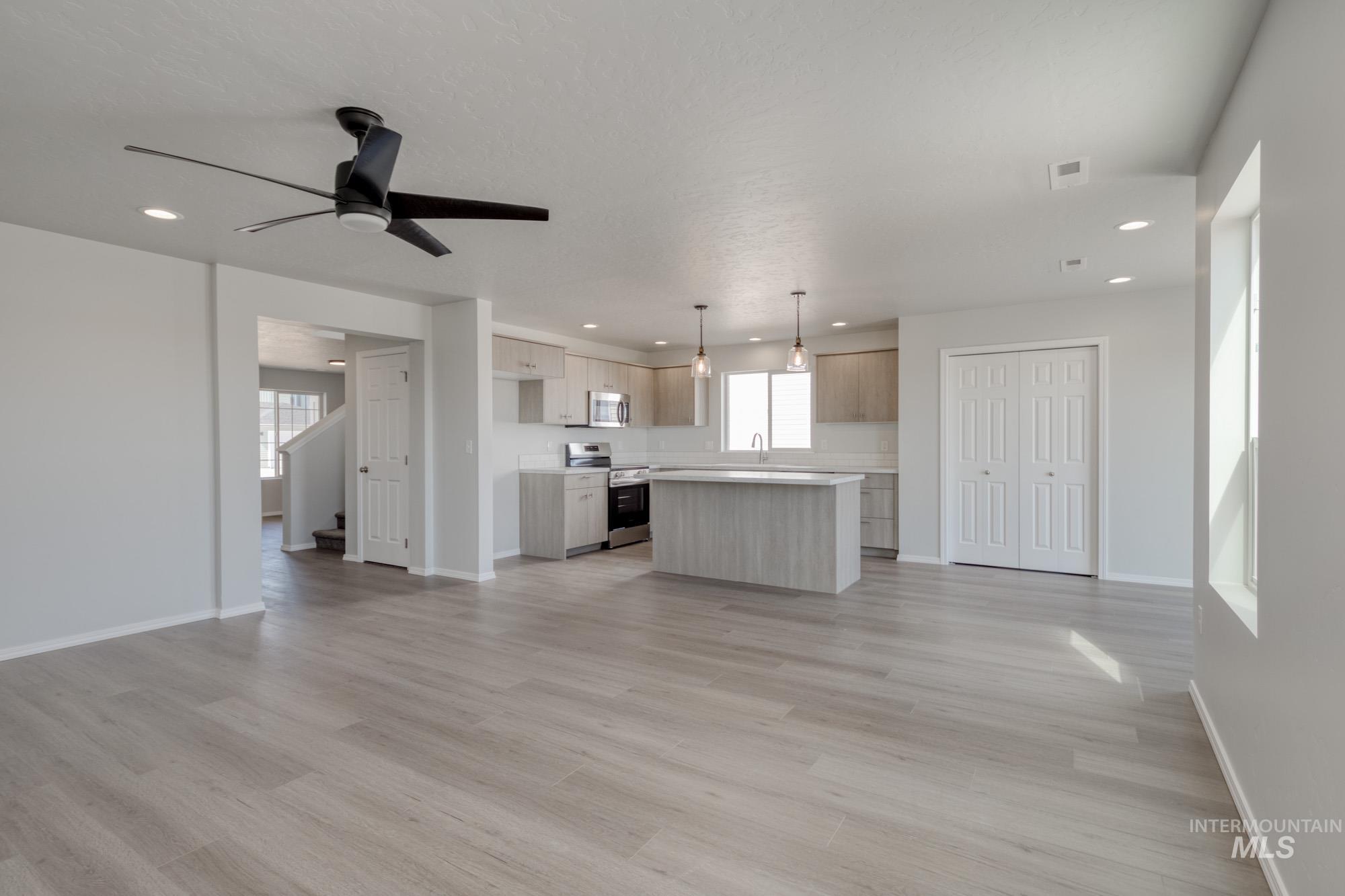 Unfurnished living room featuring light wood-style flooring, a ceiling fan, and recessed lighting