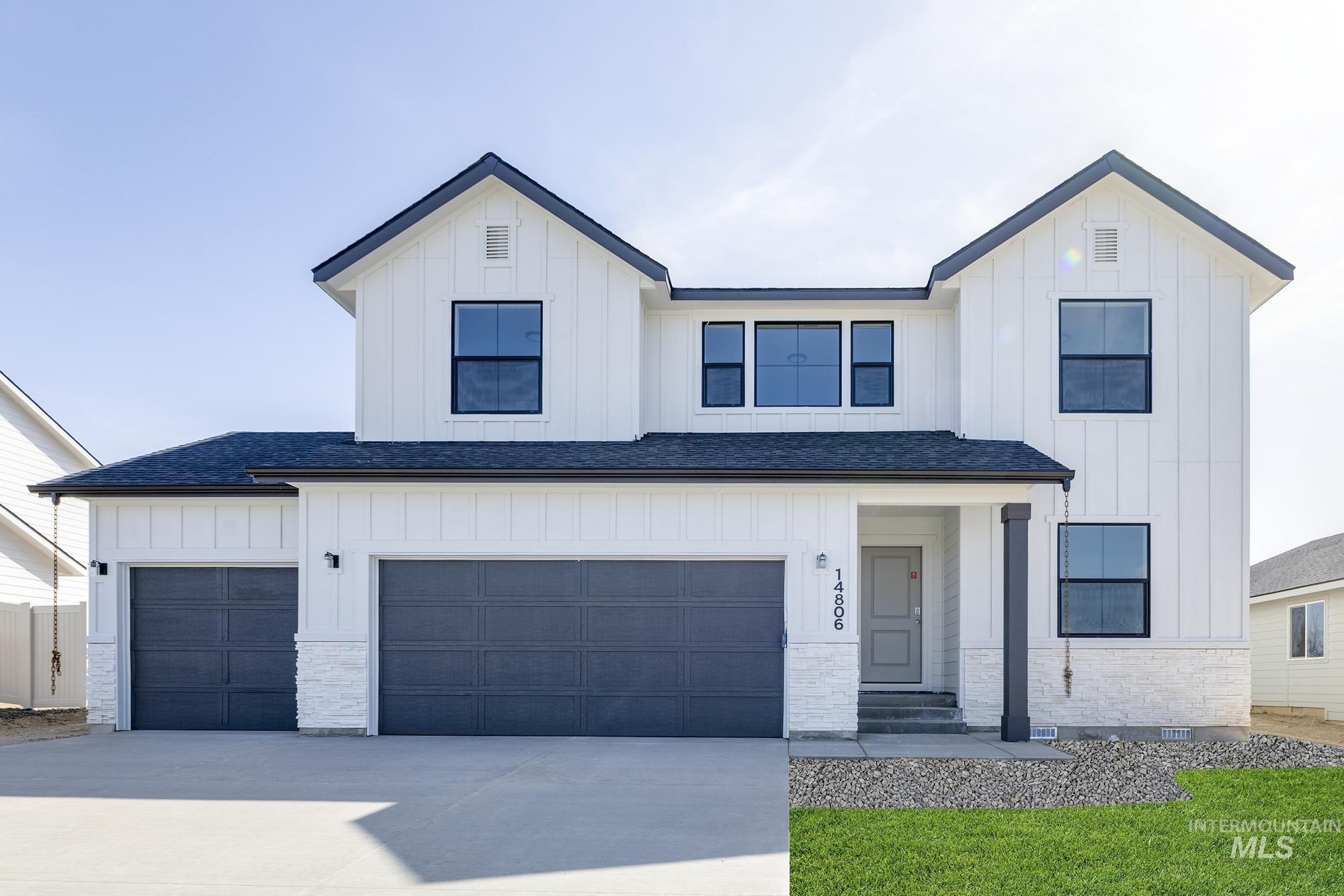 Modern farmhouse style home with board and batten siding, driveway, and a shingled roof
