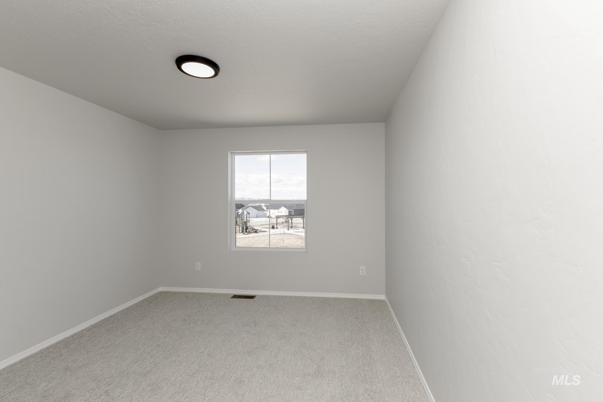 Empty room featuring light colored carpet and baseboards
