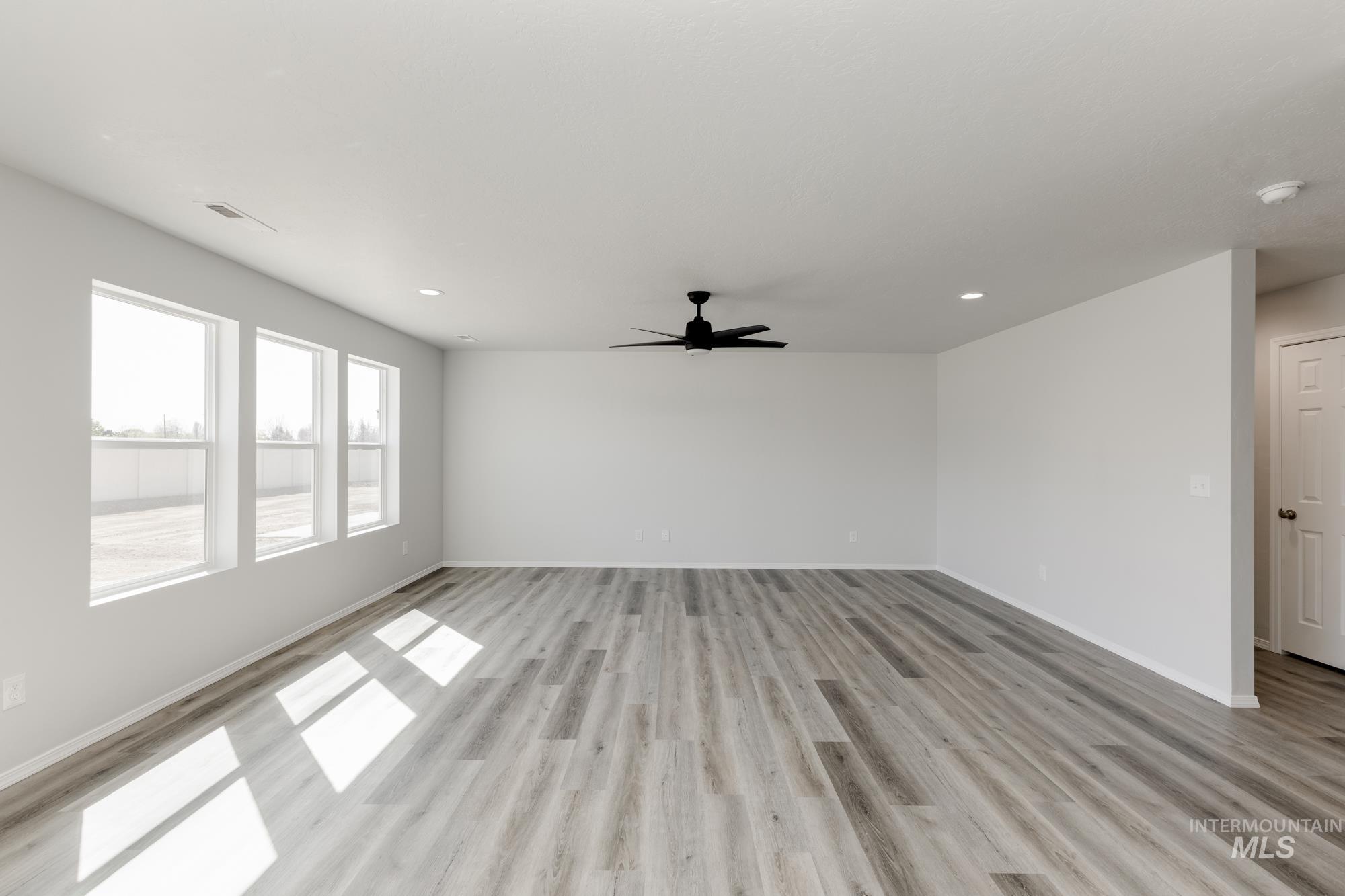 Unfurnished living room featuring light wood-style flooring, a ceiling fan, and recessed lighting