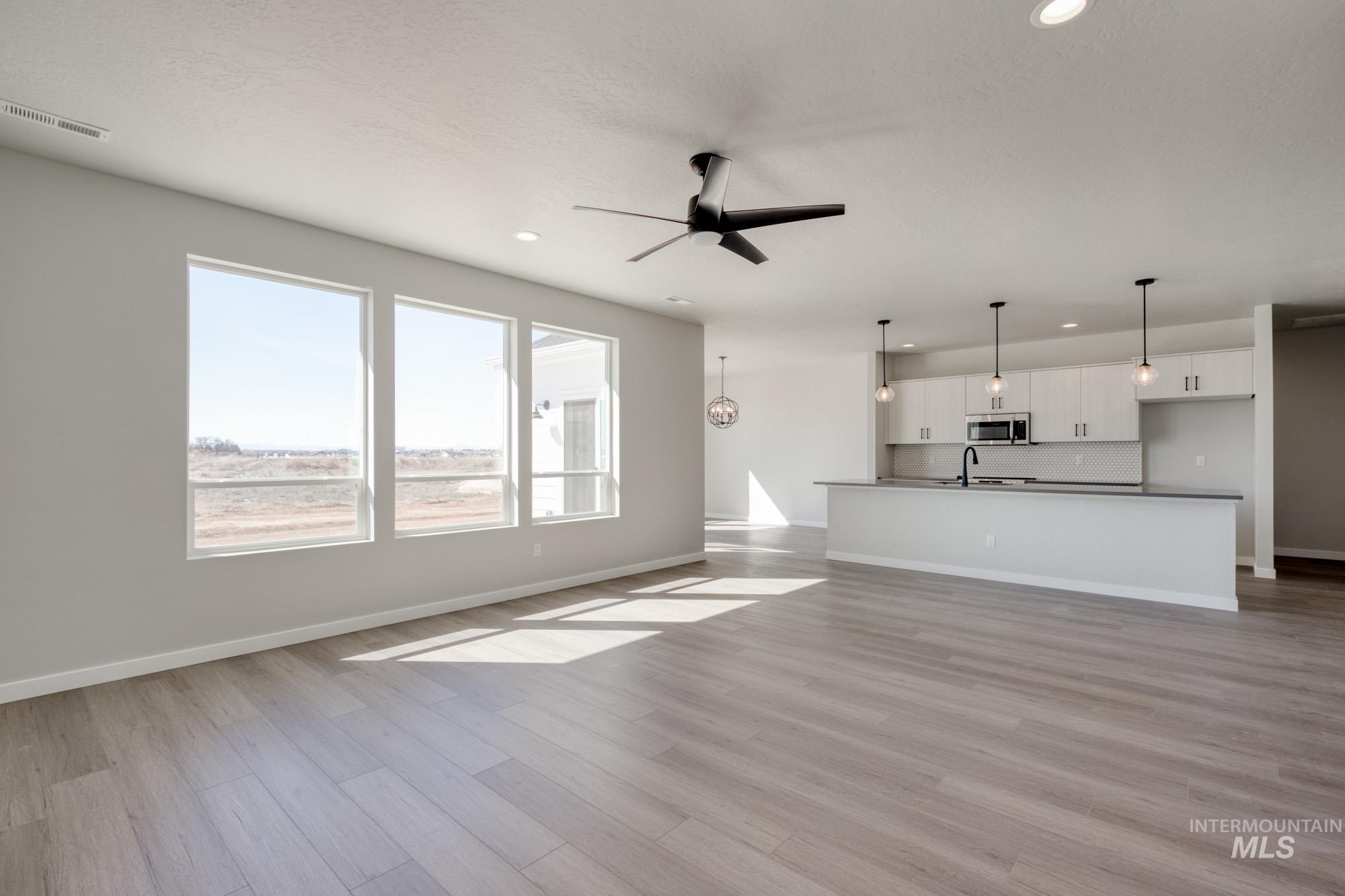 Unfurnished living room with ceiling fan, light wood-style floors, and recessed lighting